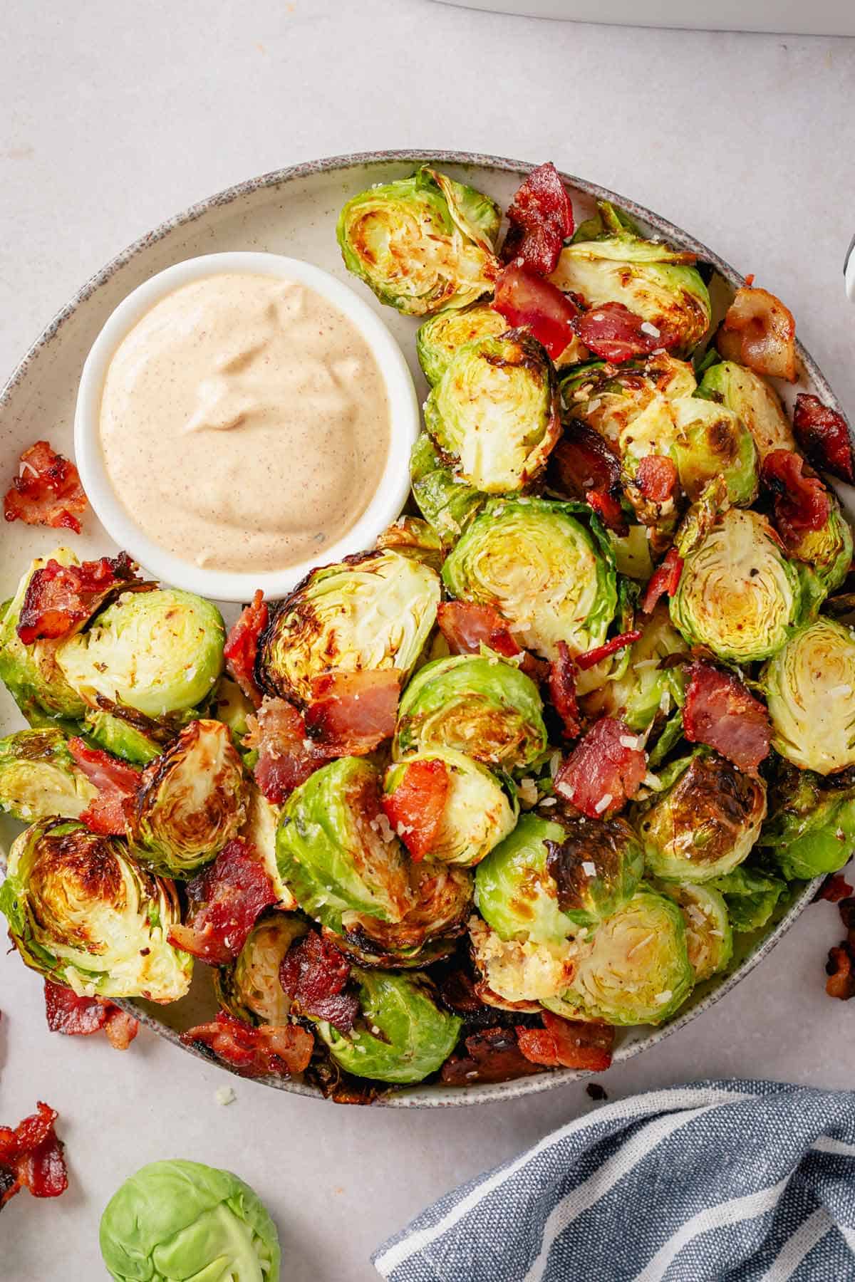 air fryer brussel sprouts with bacon and parmesan on a plate with chipotle aioli sauce