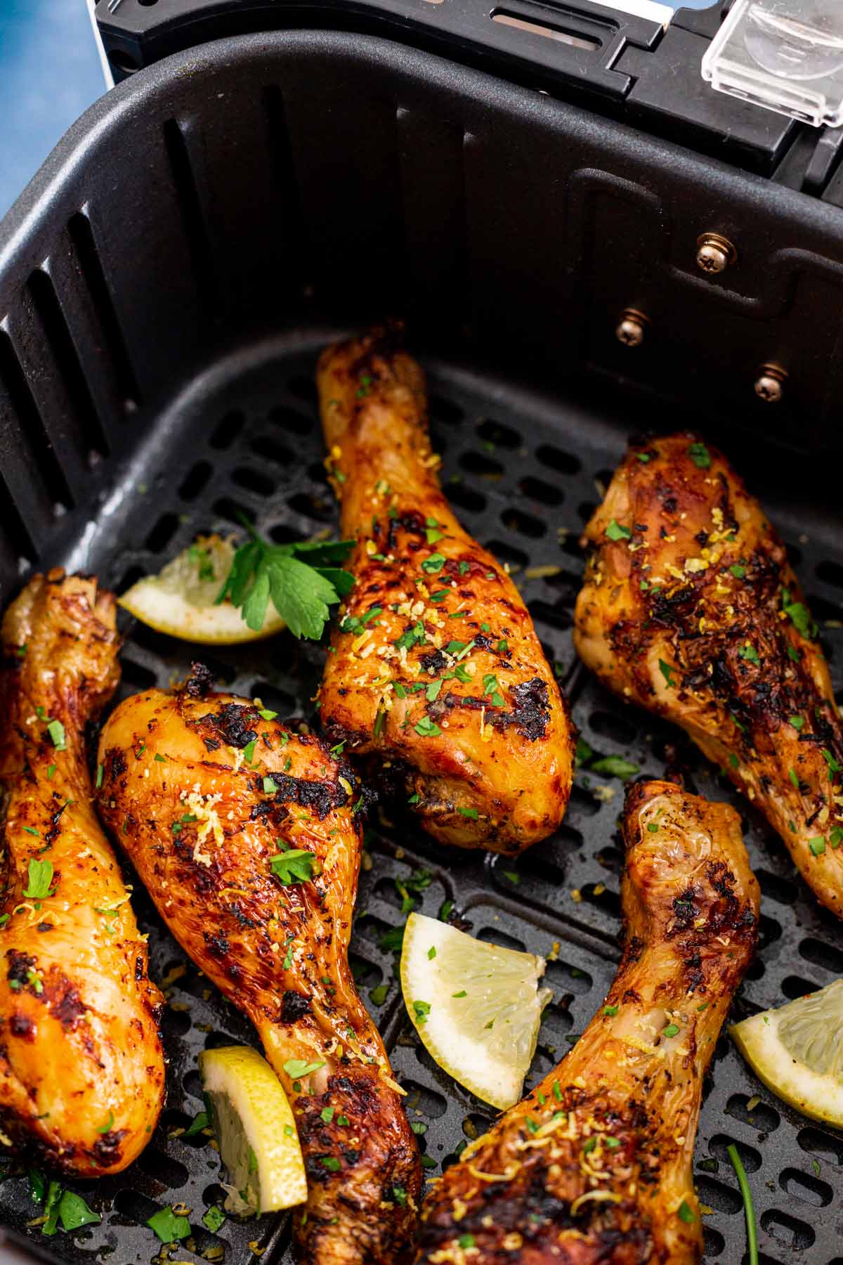 cooked lemon garlic chicken legs in air fryer basket