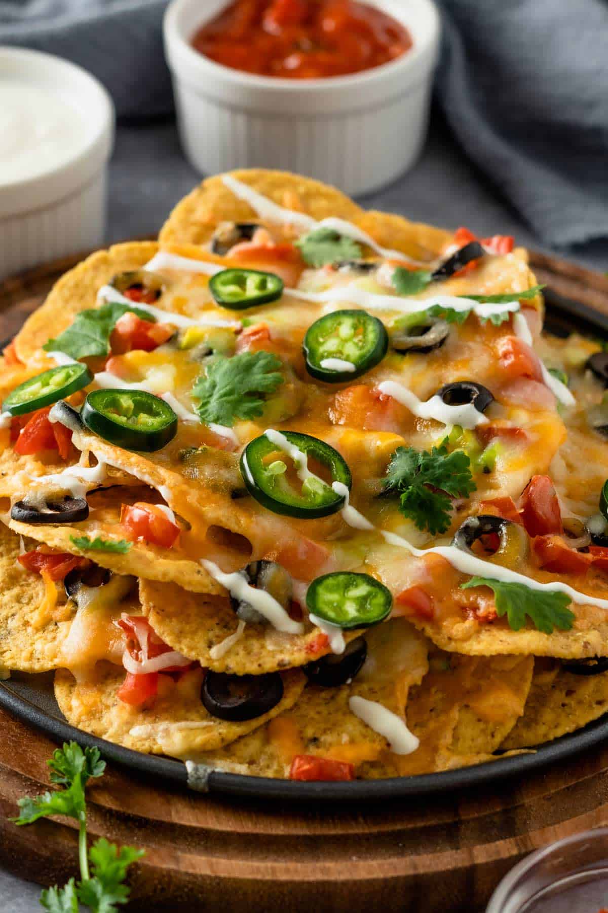 cheesy nachos with toppings on wooden board