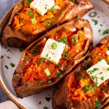 three baked sweet potatoes with butter and green onion