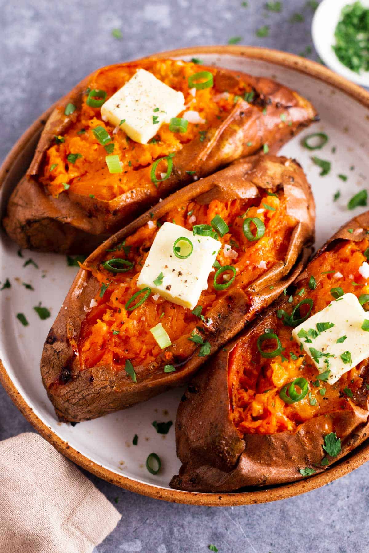 three baked sweet potatoes with butter and green onion