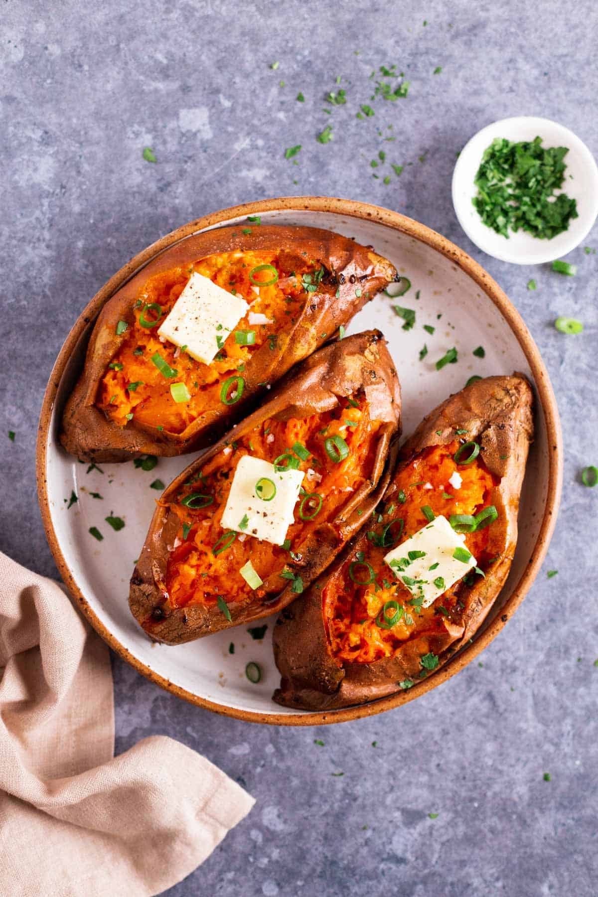 three baked sweet potatoes with butter and green onion