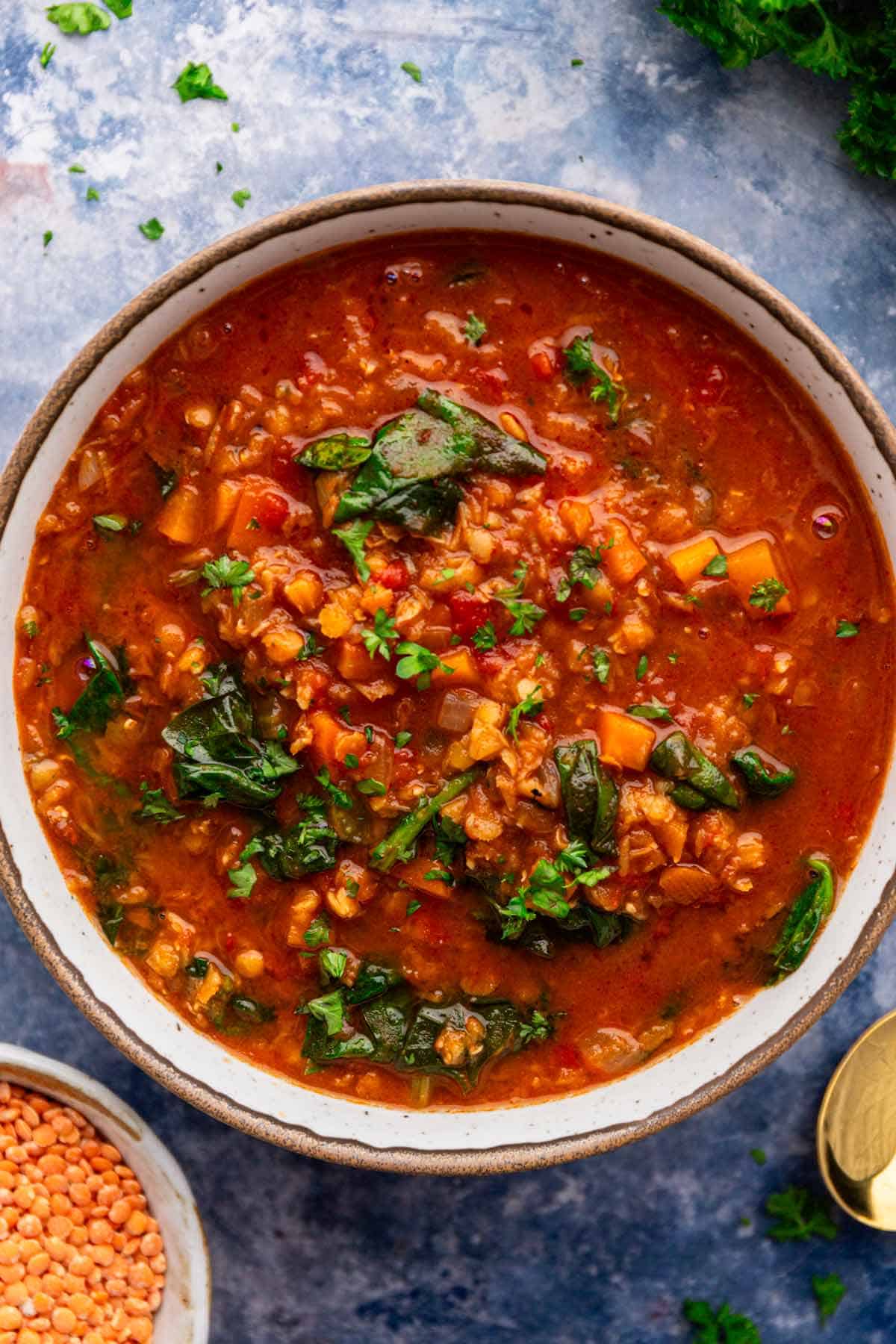 a bowl of red lentil soup with spinach.