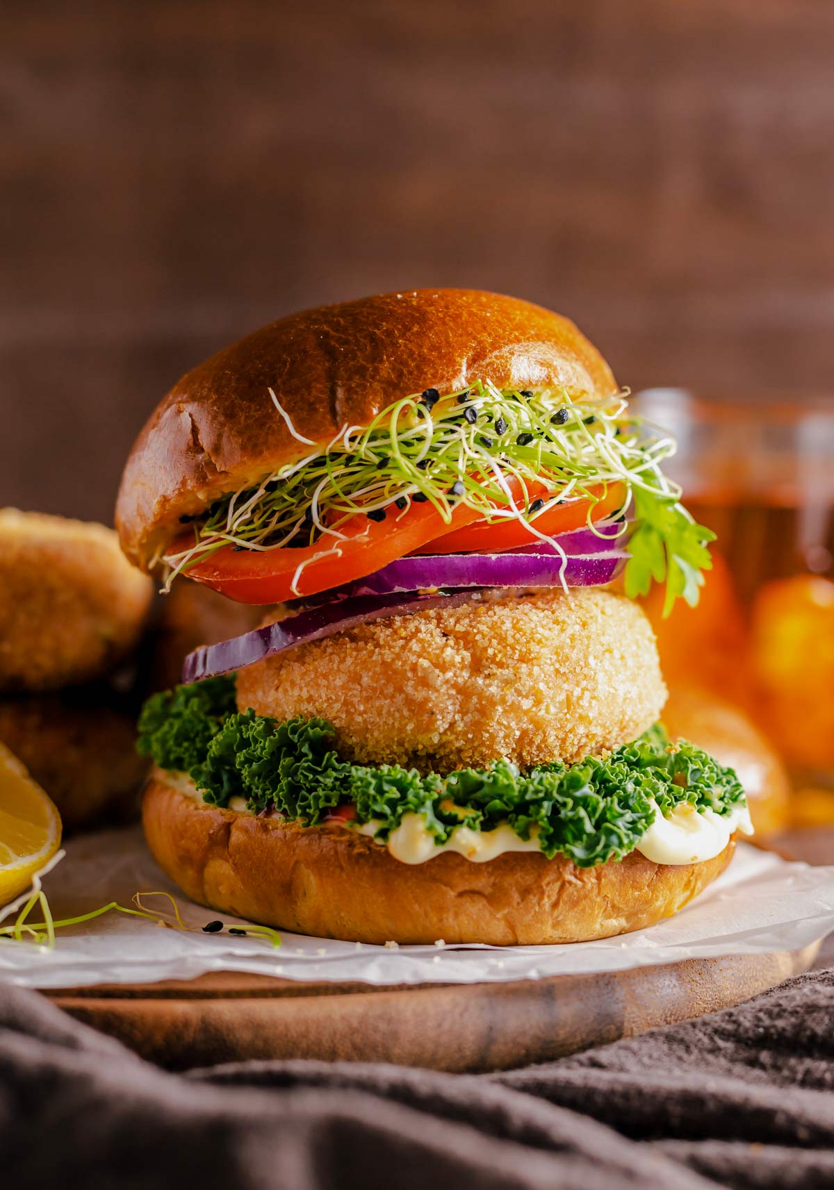 salmon patties served between burger buns, greens, tomato, red onion