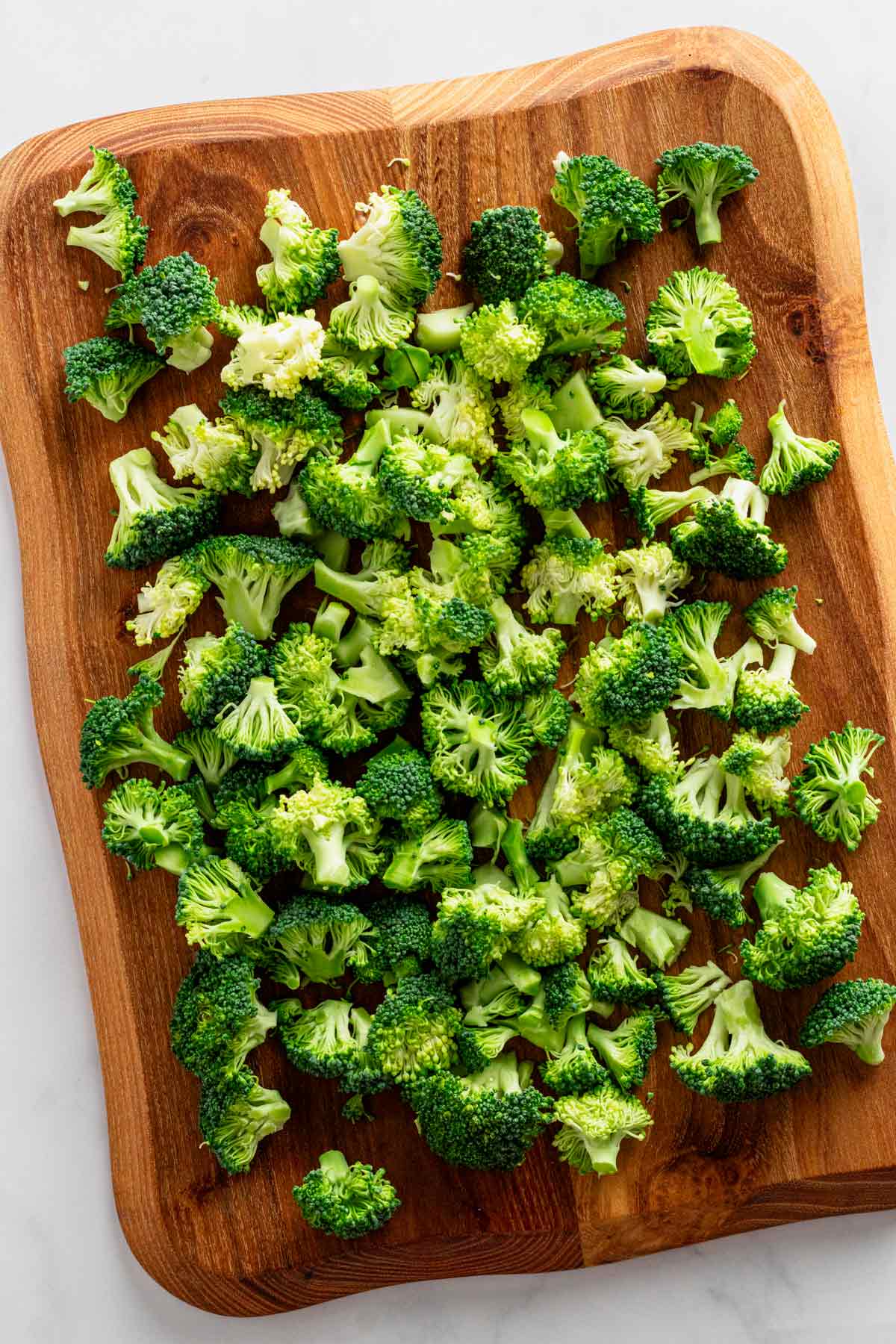 broccoli florets on wooden cutting board.