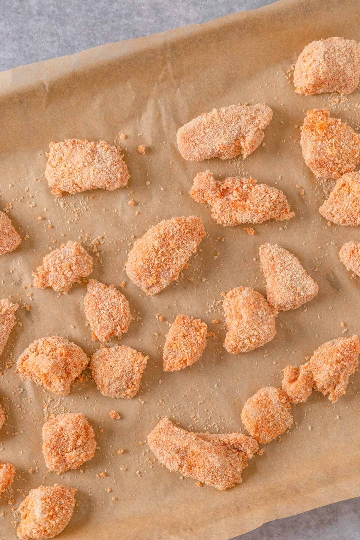 buffalo chicken pieces in breadcrumbs on a baking sheet before baking