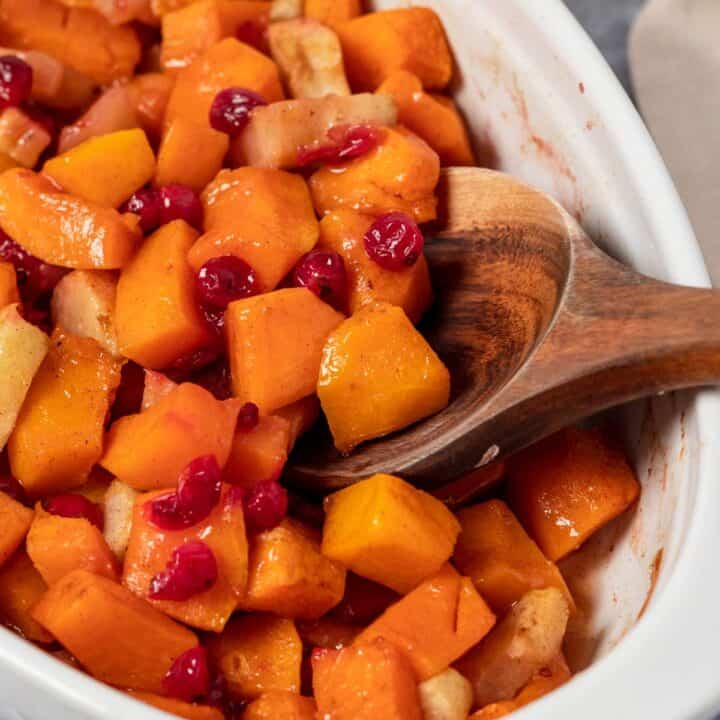 squash casserole in oval baking dish with apples and cranberries