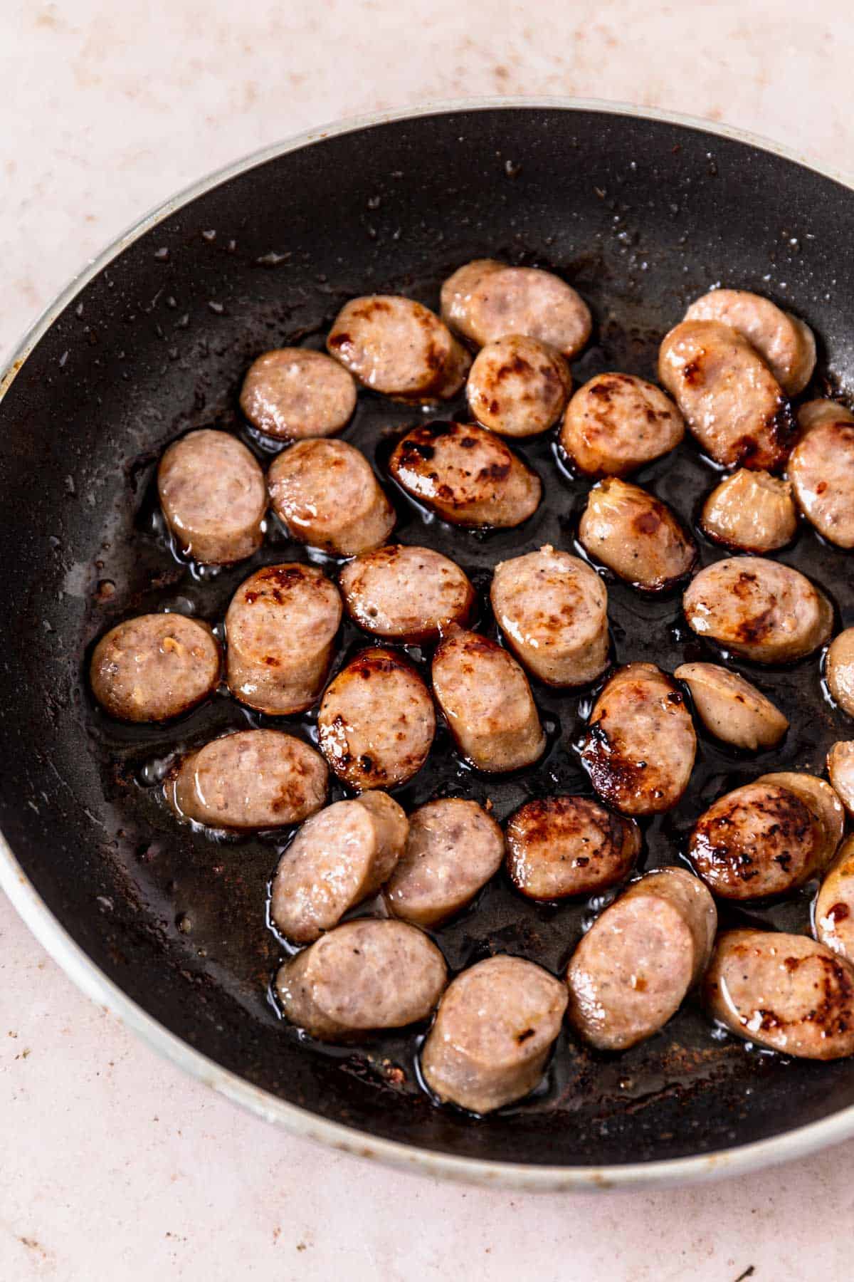 pork sausage slices cooking in the skillet