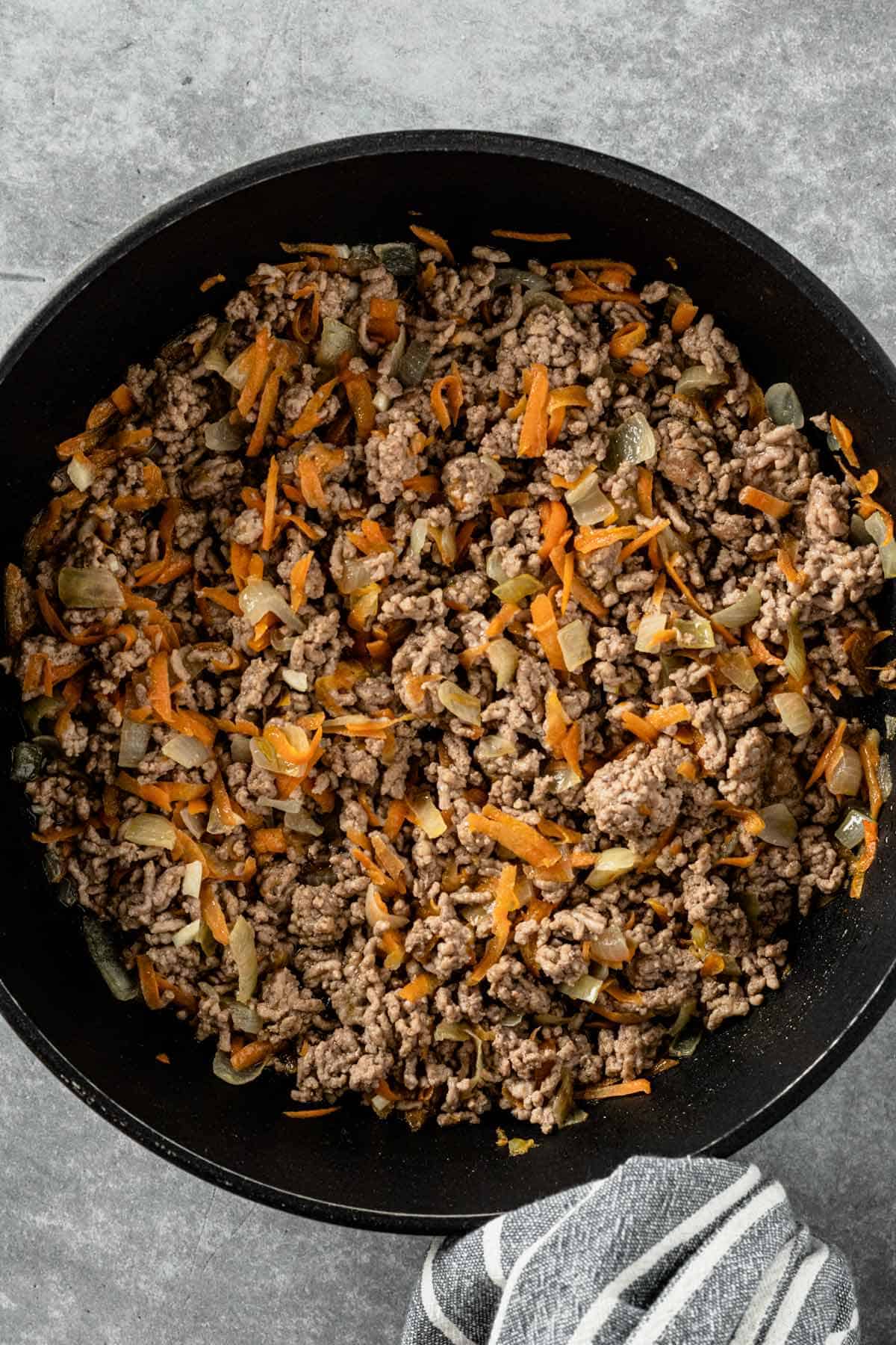 browned ground beef in pan with carrots and onions
