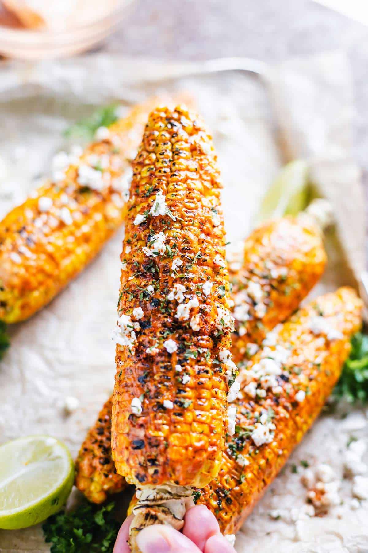 side angle view bite shot of cajun on the cob on a white plate with lime and cilantro