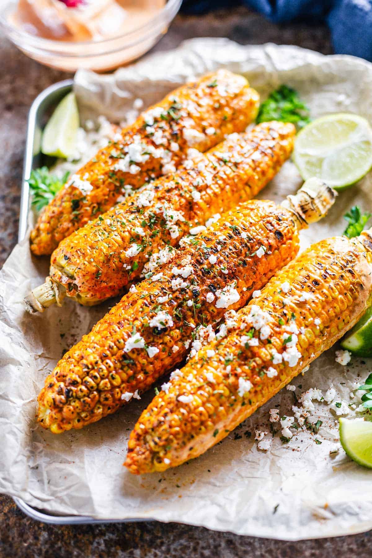 side angle view shot of cajun on the cob on a white plate with lime and cilantro