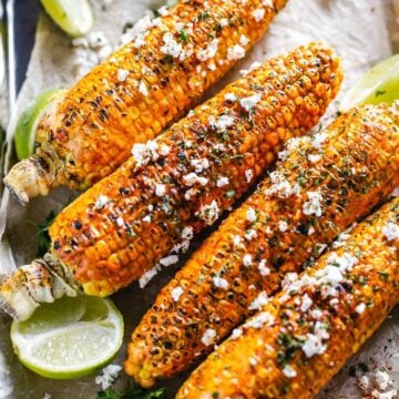 flat lay shot of 4 cajun corn on the cob with feta cheese and parsley