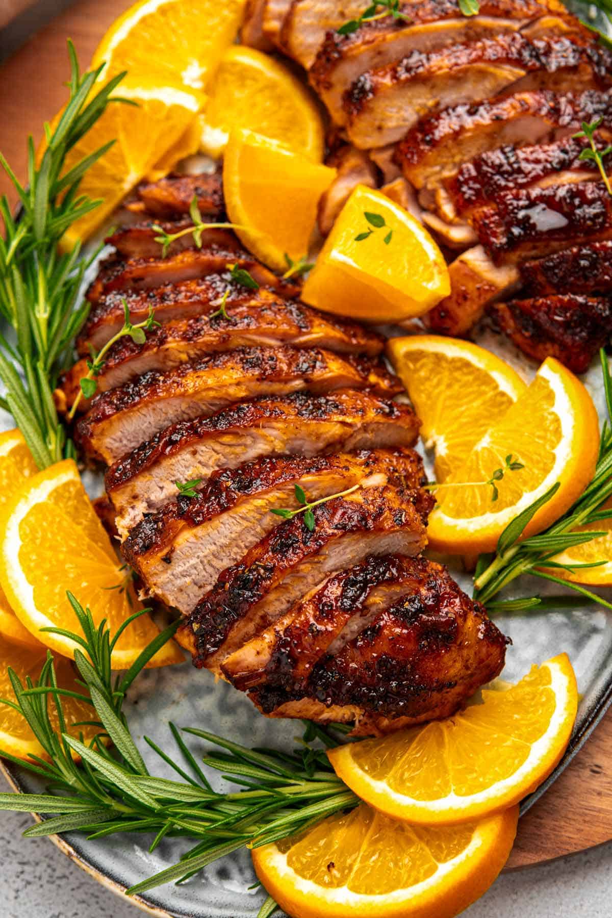 two sliced turkey breasts with oranges and rosemary.