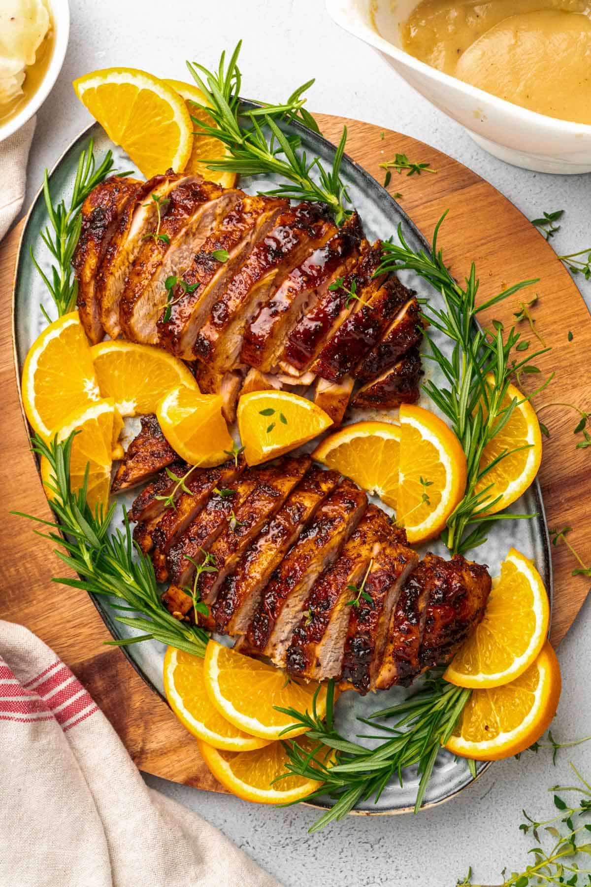 two sliced turkey breasts with oranges and rosemary.