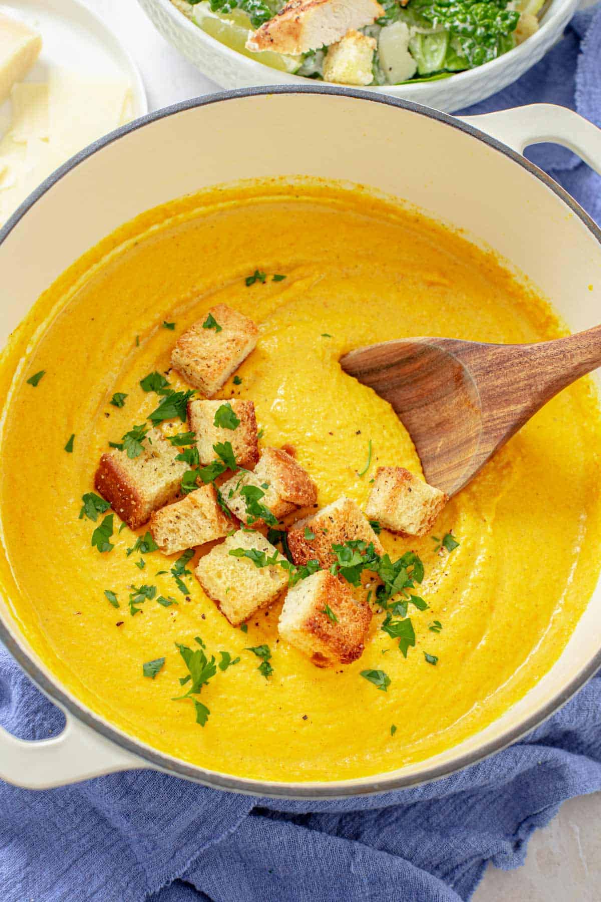carrot ginger turmeric soup with croutons in a white pot