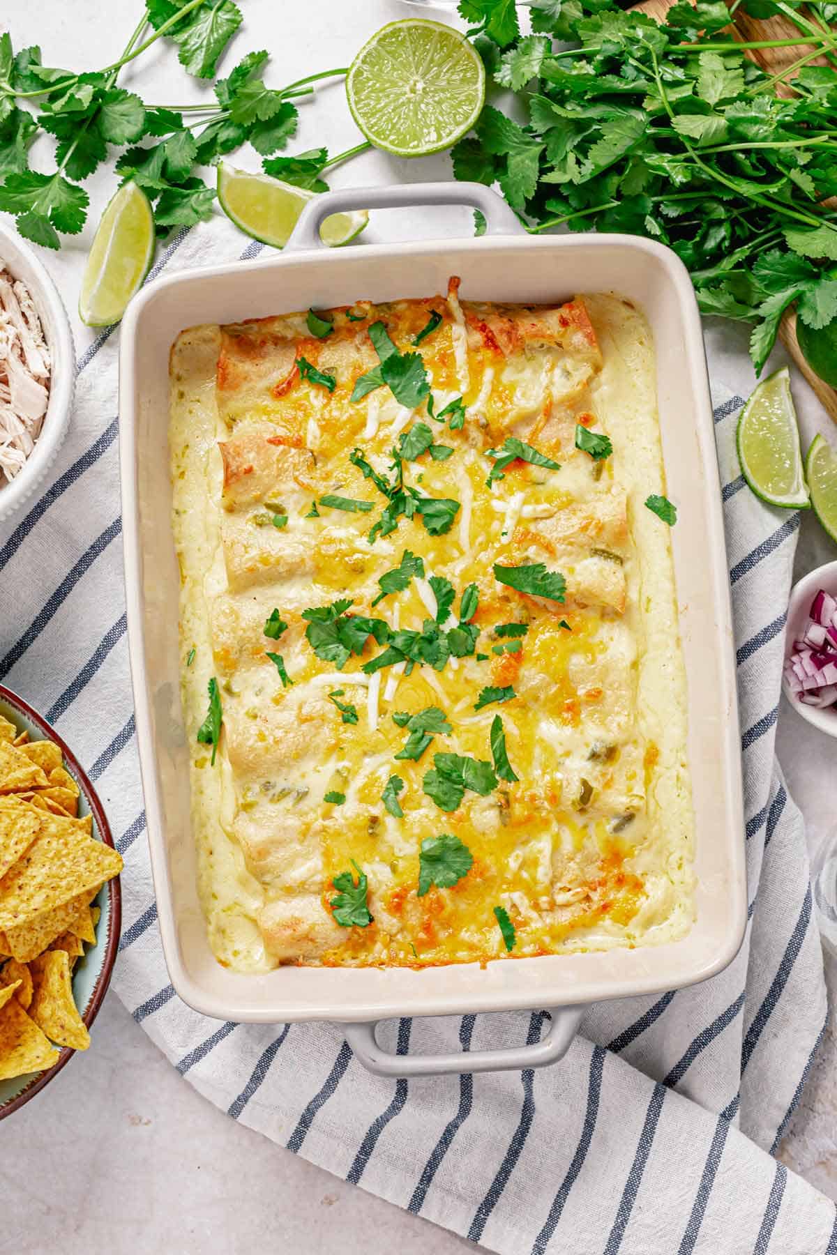 an over head shot of chicken enchilada in white sauce in a baking dish garnished with cilantro leaves in the middle