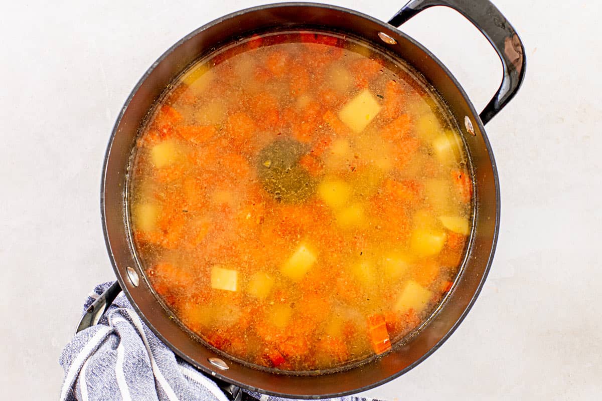 vegetables simmering in a black pot for chicken kale soup