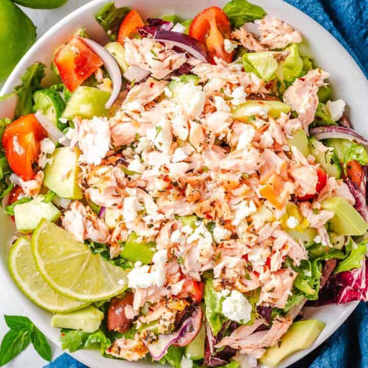 final shot of a shredded baked salmon ina bowl with lettuce and vegetables