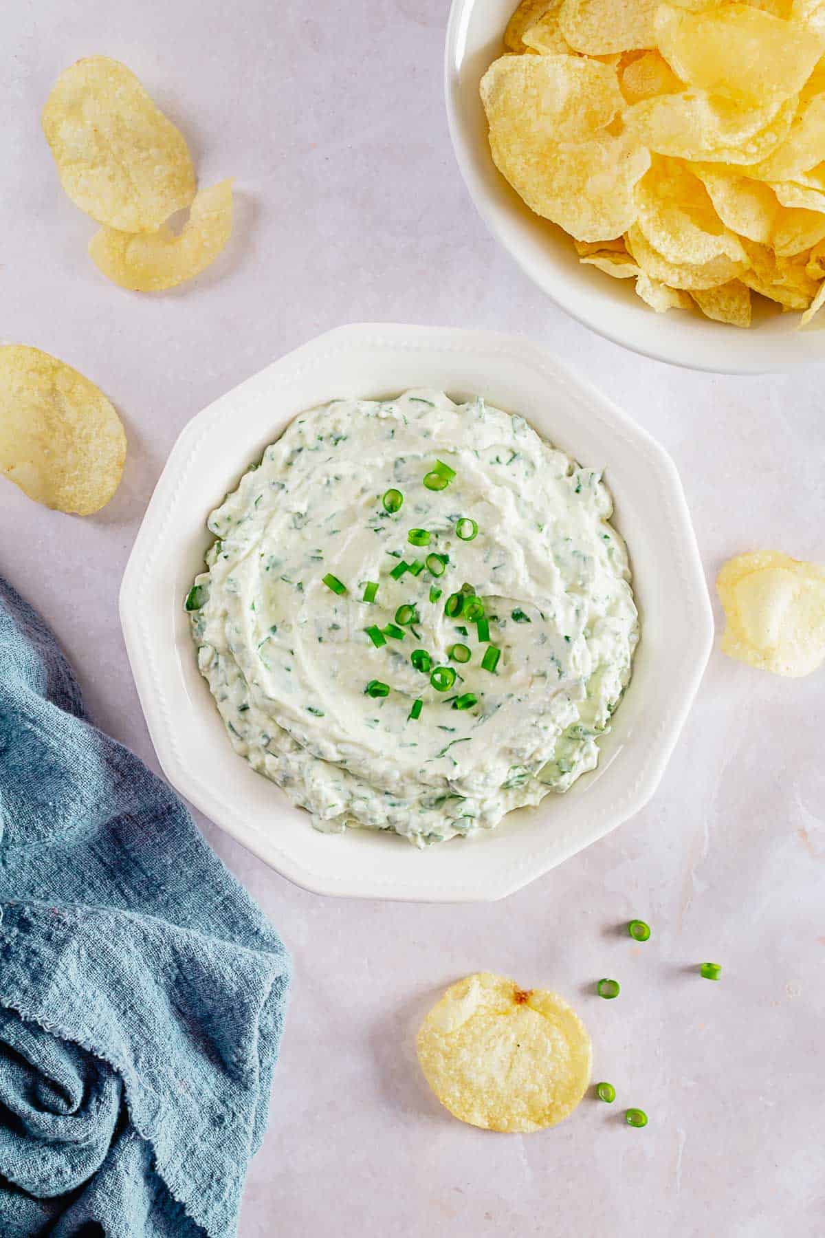 final shot of cold spinach dip with green onions in a white bowl