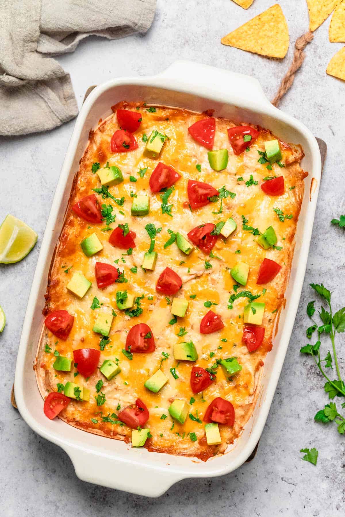 chicken enchilada casserole with tomatoes, avocado and cilantro