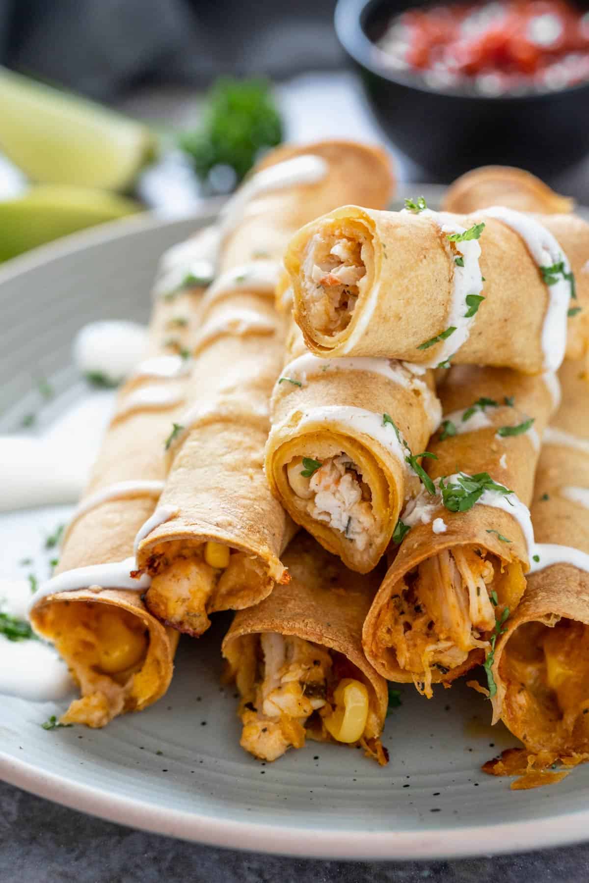 Creamy Chicken Taquitos stacked on top of each other and drizzled with sriracha mayonnaise