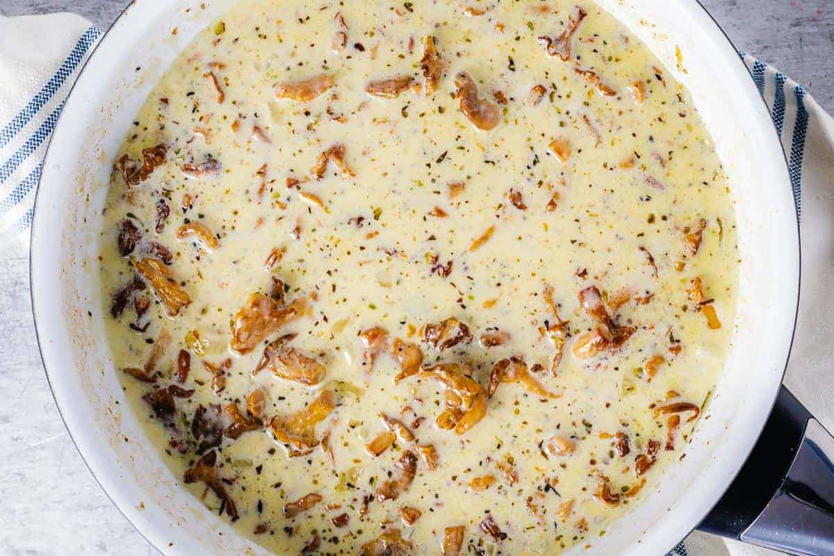 creamy chanterelle mushrooms cooking in a white pan