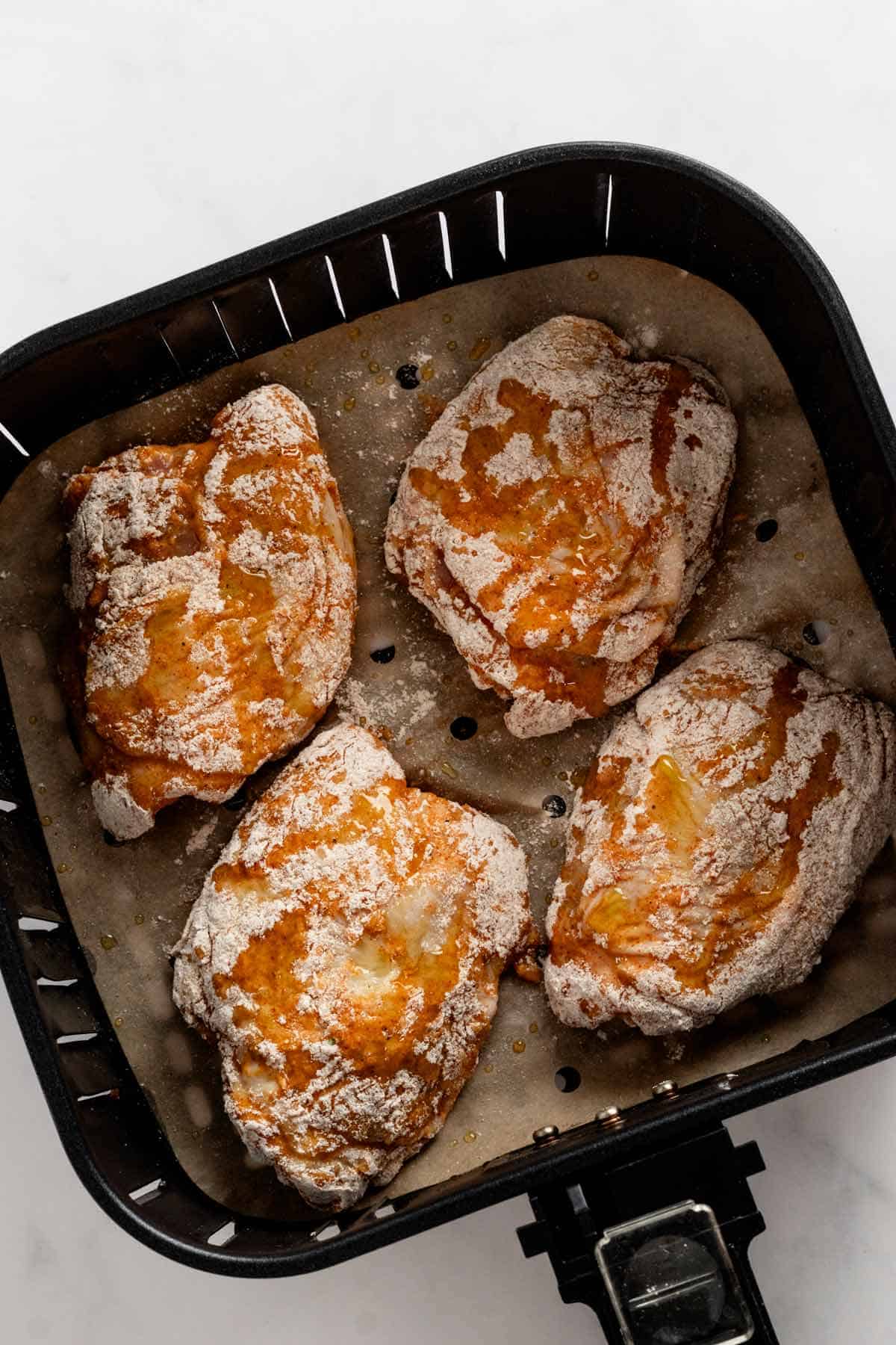 four chicken thighs in air fryer basket before cooking.