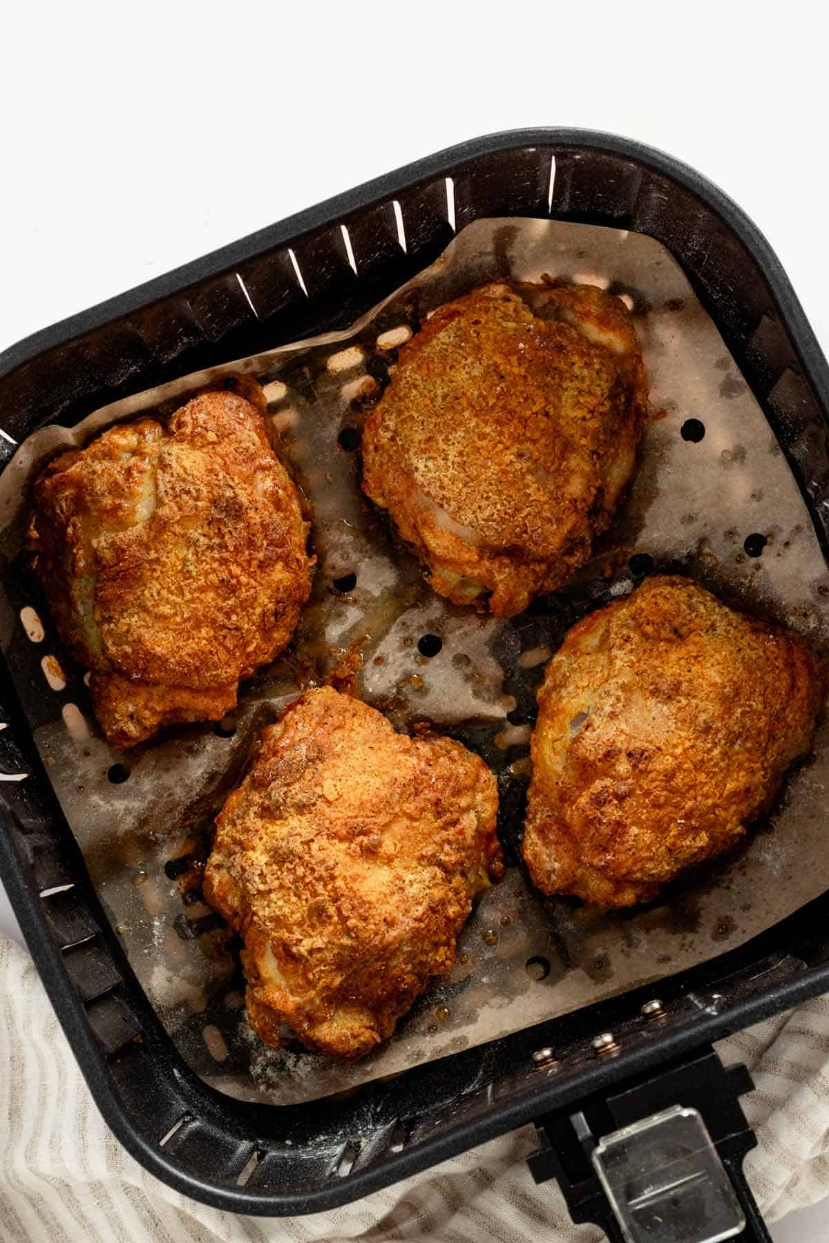 four chicken thighs in air fryer basket after cooking.