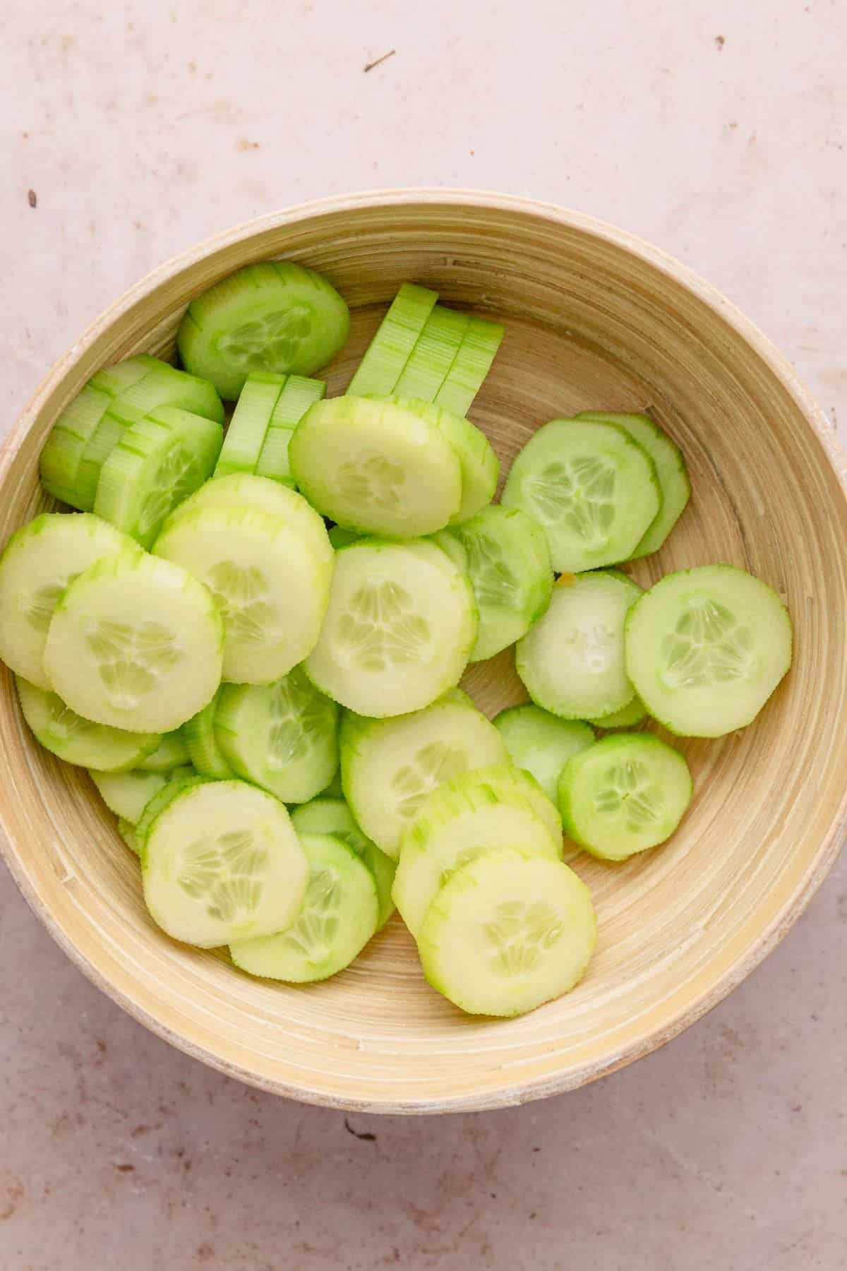 peeled and sliced cucumbers in a bowl.