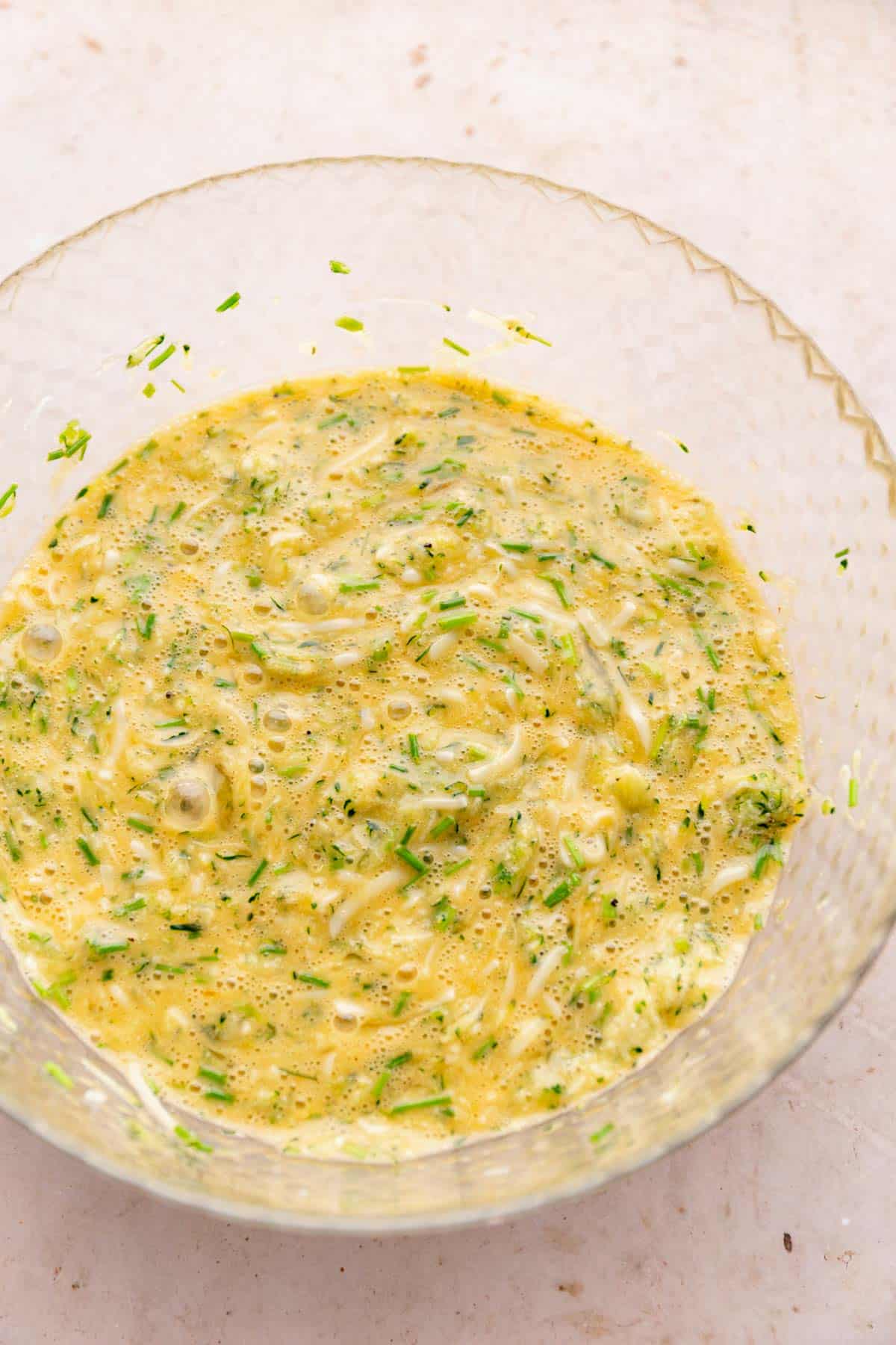 a bowl of beaten egg and zucchini.