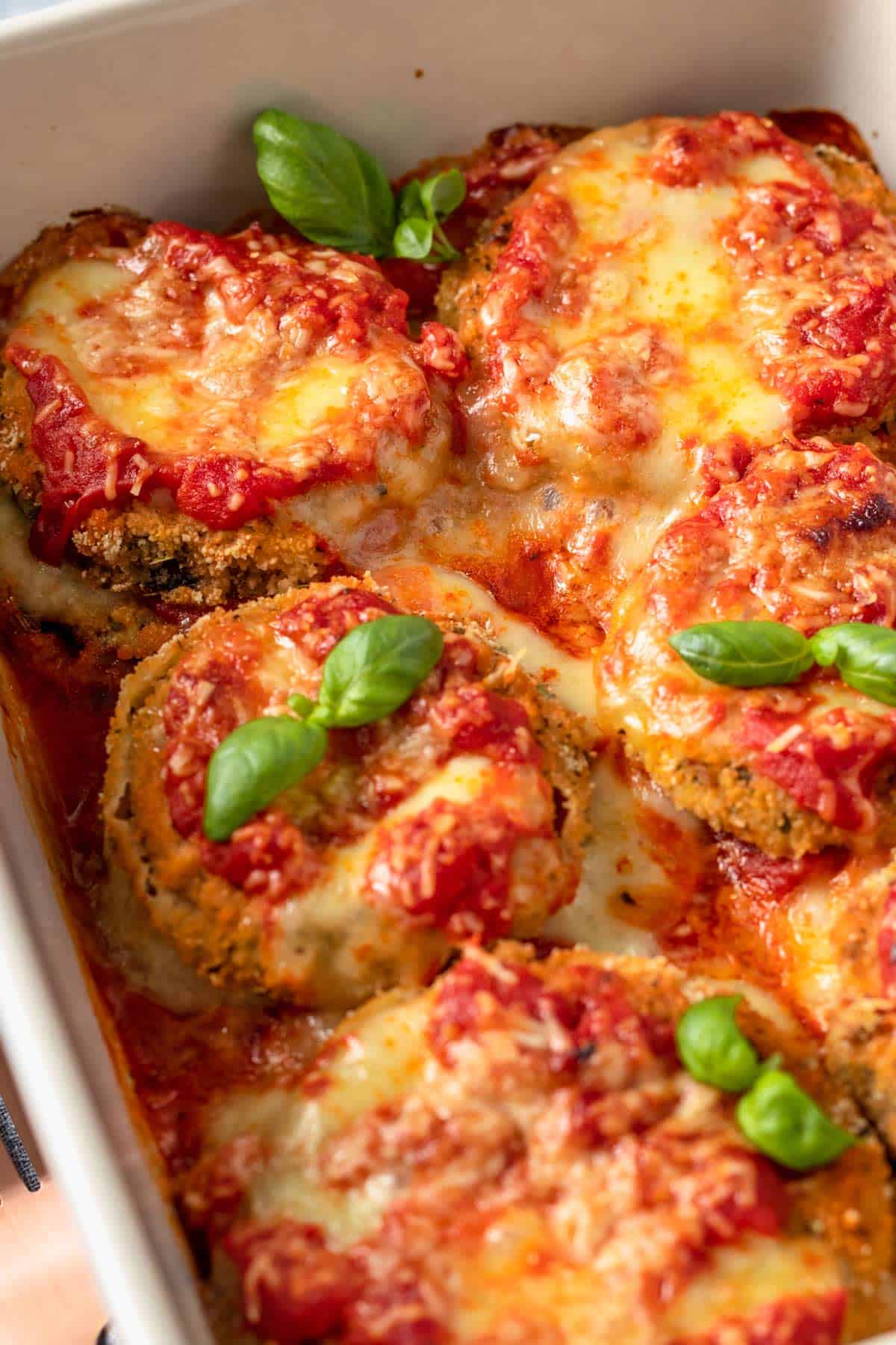 Gluten Free Eggplant Parmesan in baking dish with basil leaves