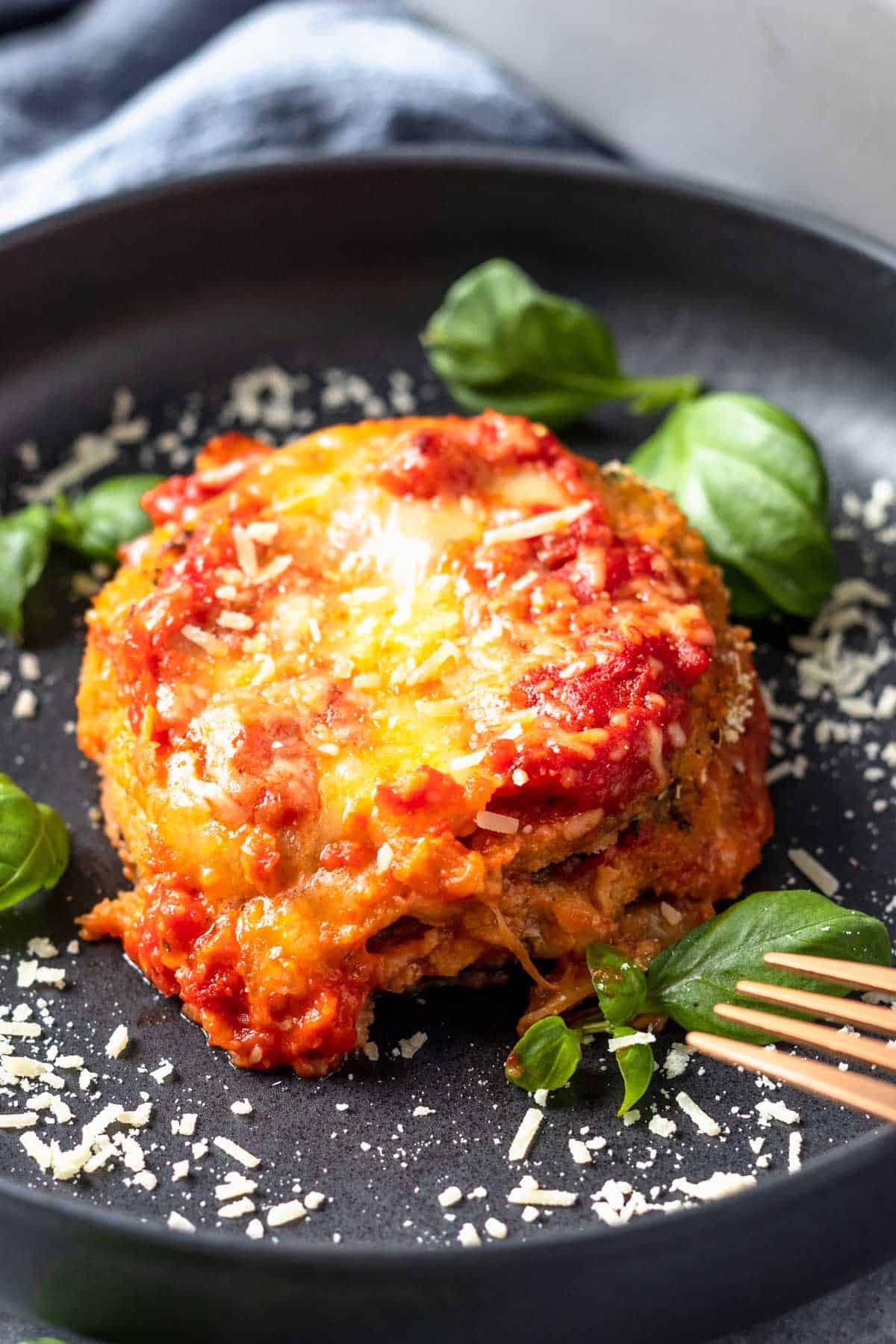 Gluten Free Eggplant Parmesan on a plate with basil leaves