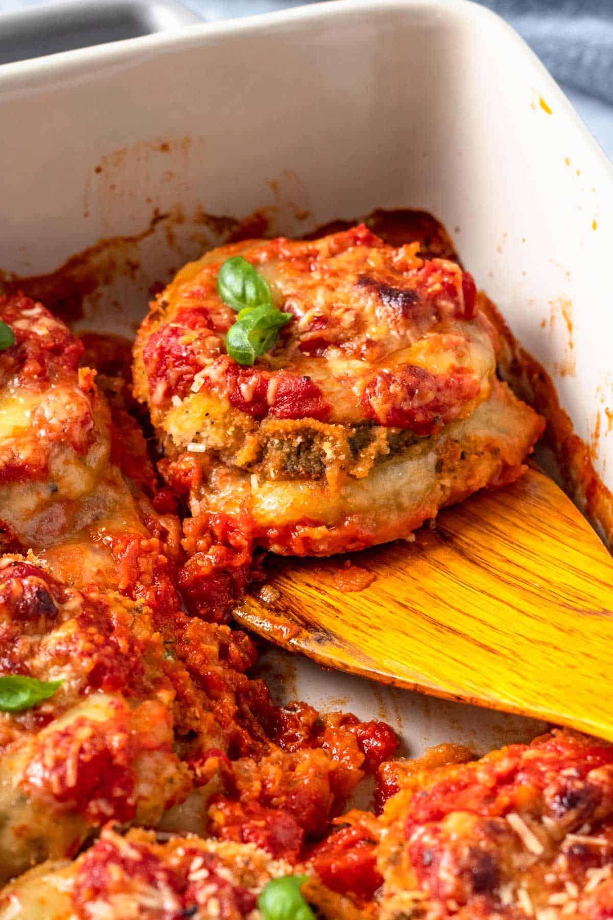 Gluten Free Eggplant Parmesan in baking dish with basil leaves