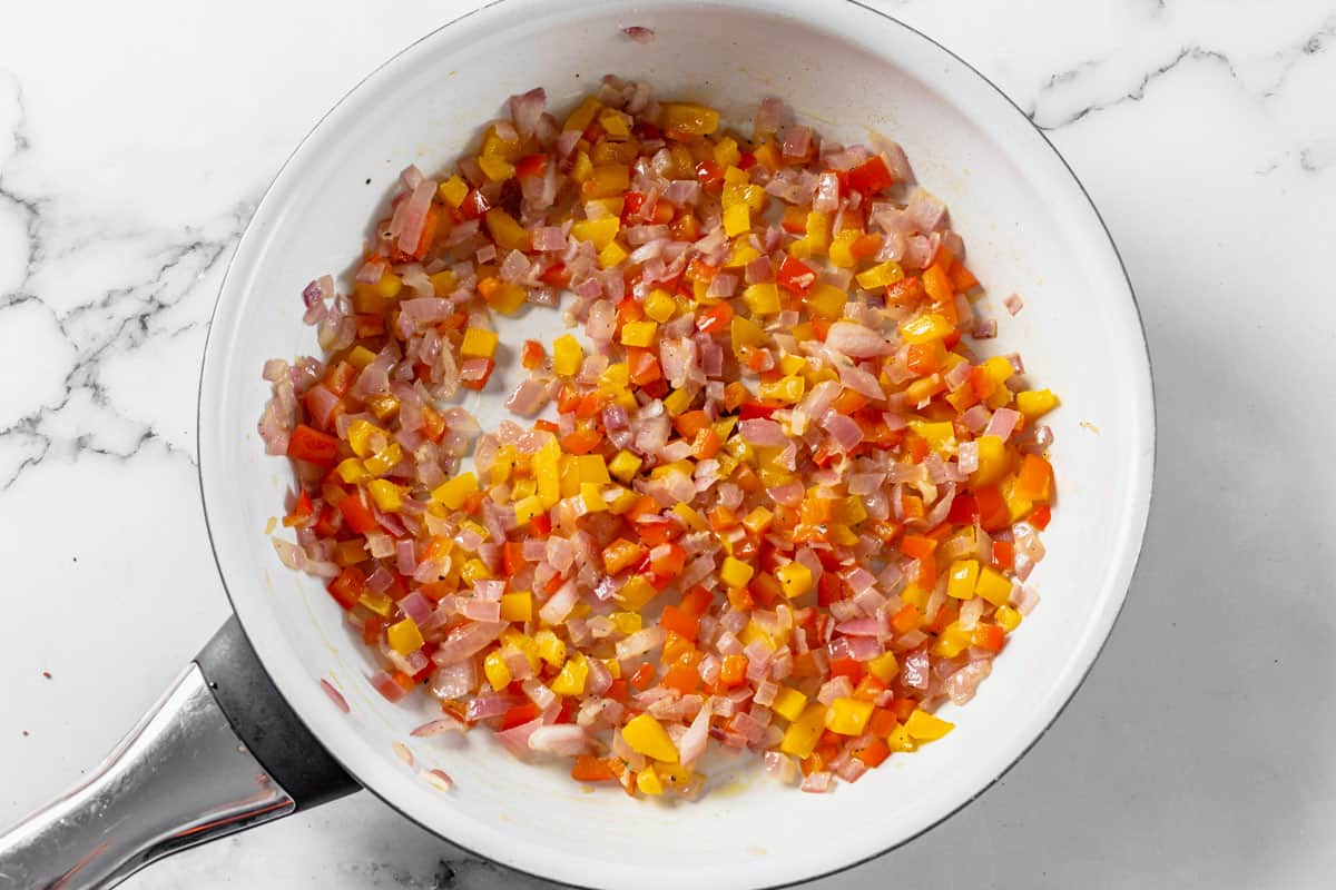 onion and bell peppers sauteing in a pan