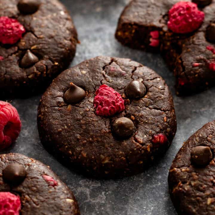 no bake dark chocolate cookies with raspberries with a dark background.