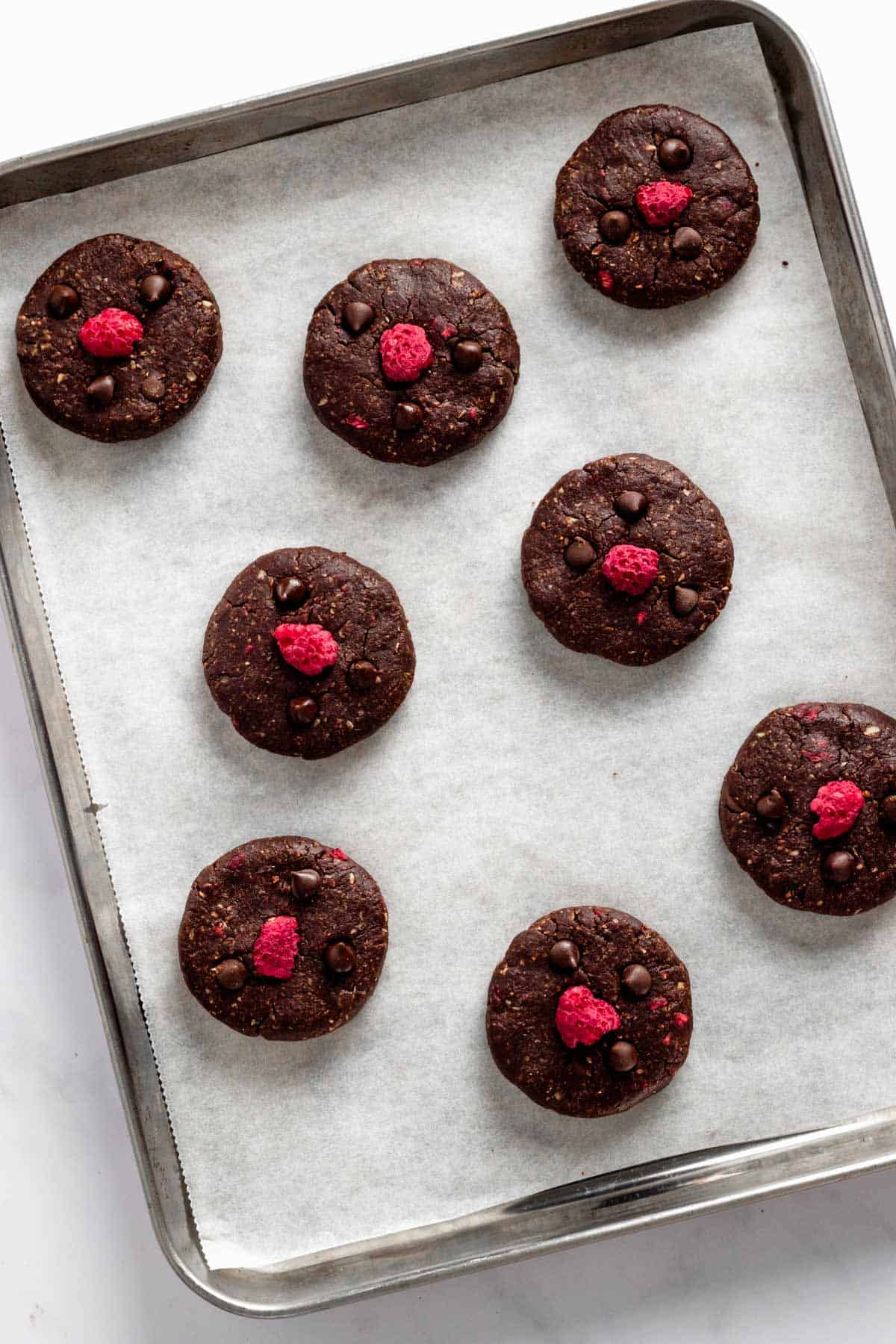 chocolate oatmeal no bake cookies with dried raspberries on a baking sheet.