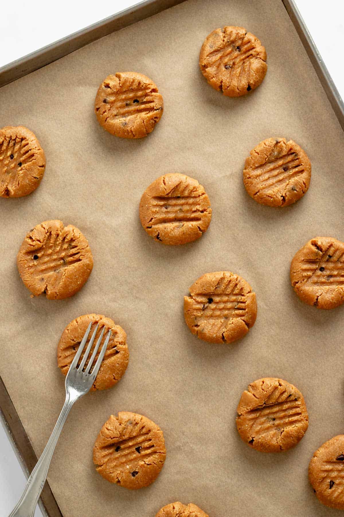 making criss cross pattern with a fork on peanut butter cookies.