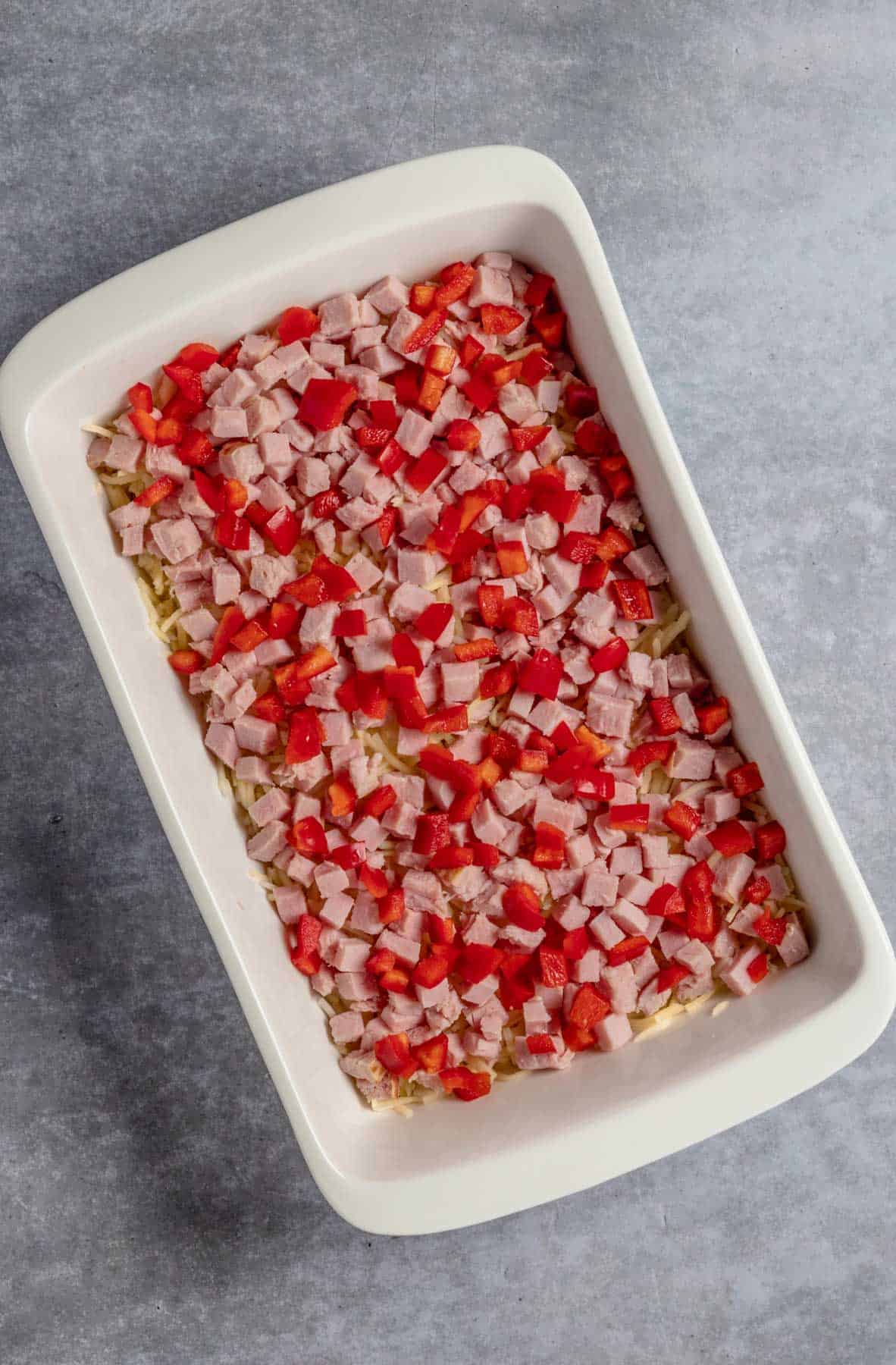 ham and bell peppers in casserole dish on top of hashbrowns