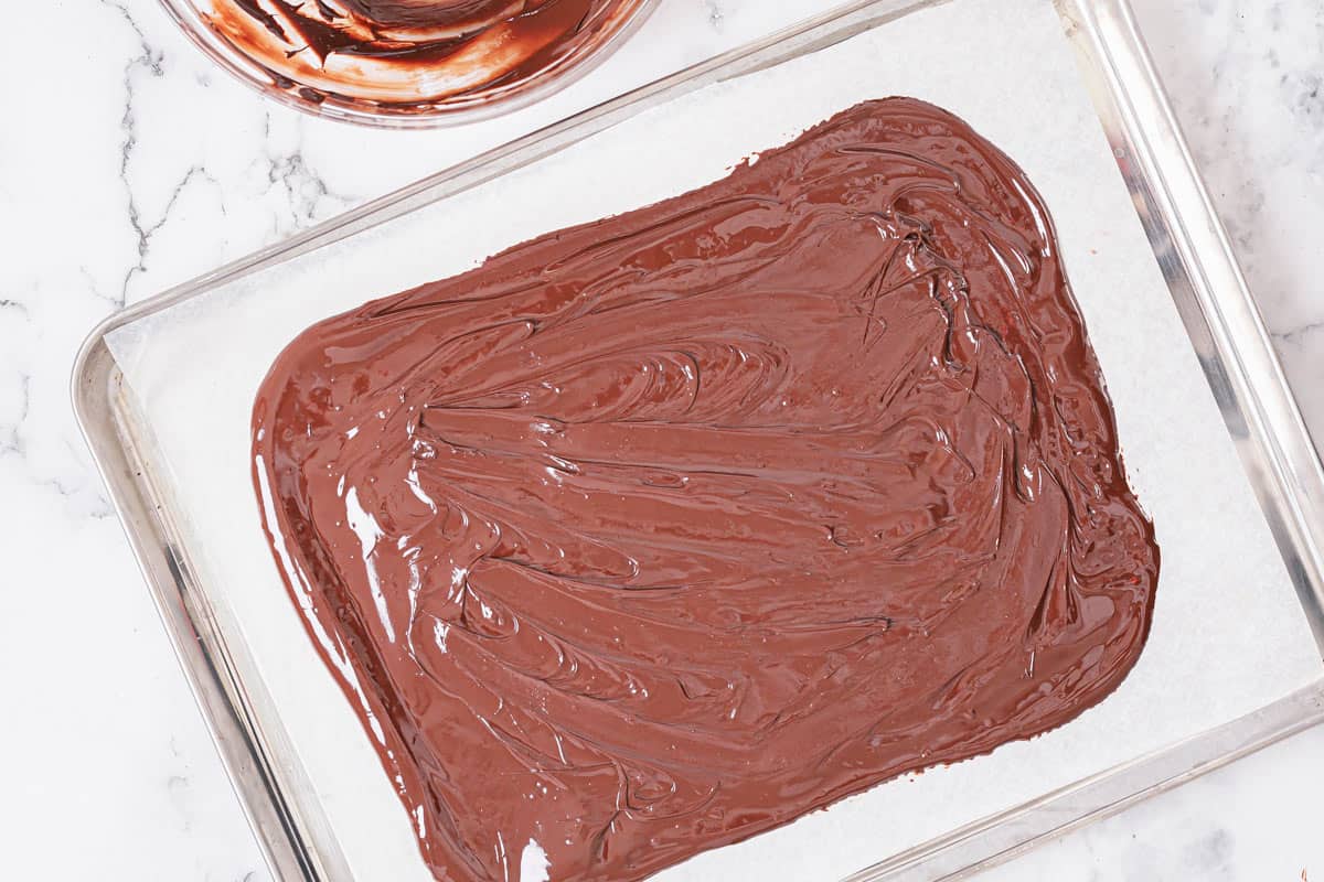 melted dark chocolate spread out on a parchment paper