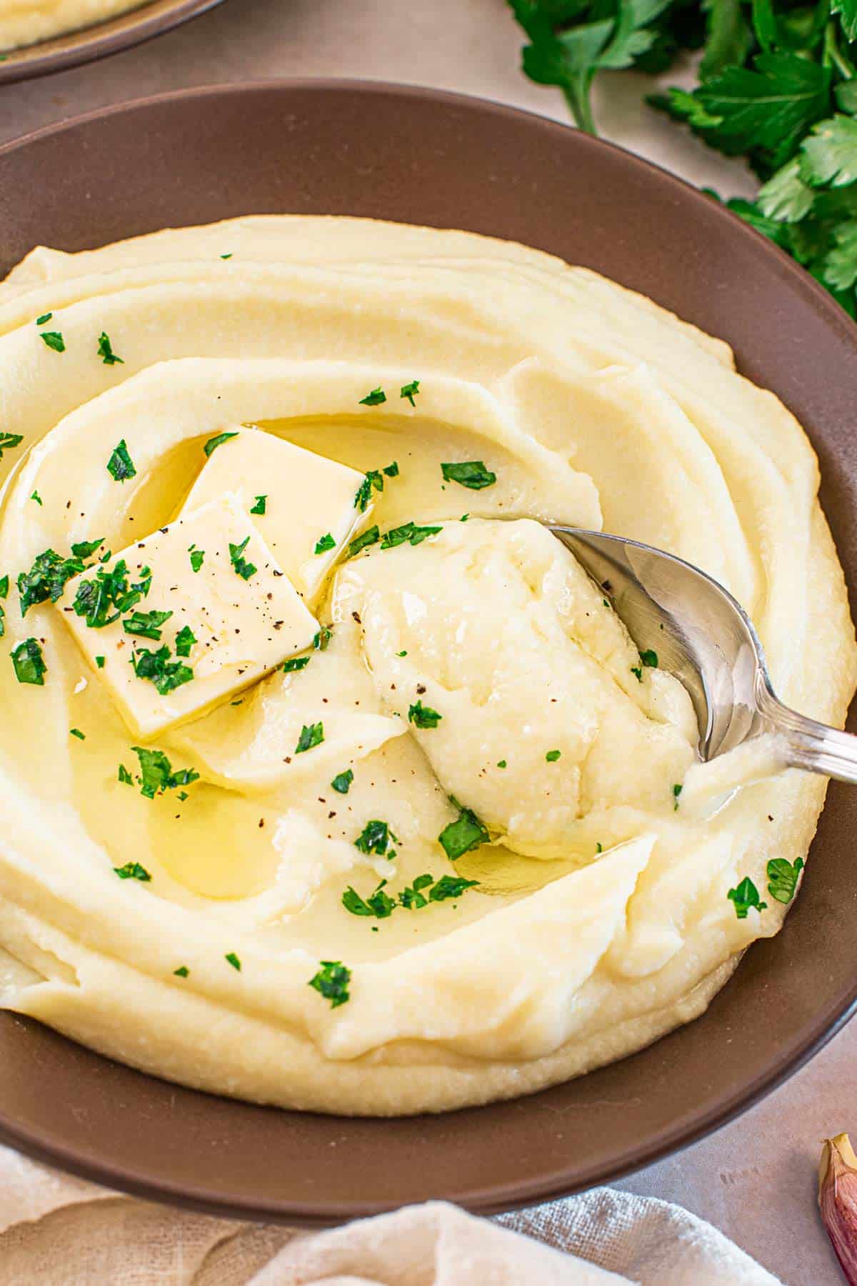 dark mashed potato and cauliflower bowl with a spoon inside