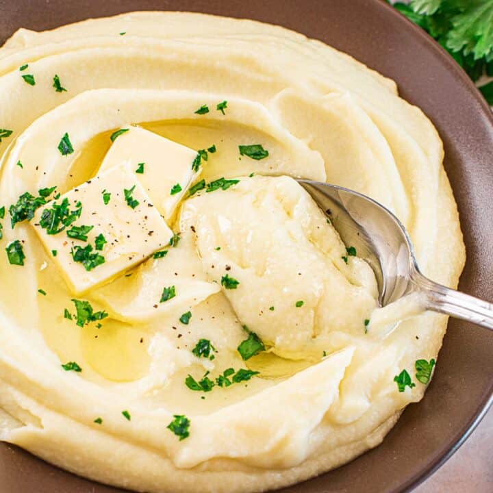 dark mashed potato and cauliflower bowl with a spoon inside