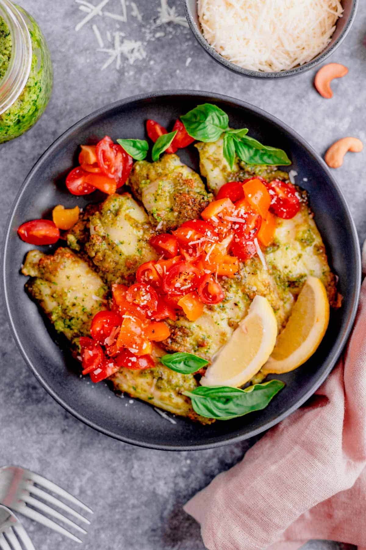 air fryer tilapia with pesto in a plate with cherry tomatoes and parmesan