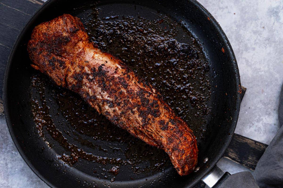 seared pork tenderloin in skillet.