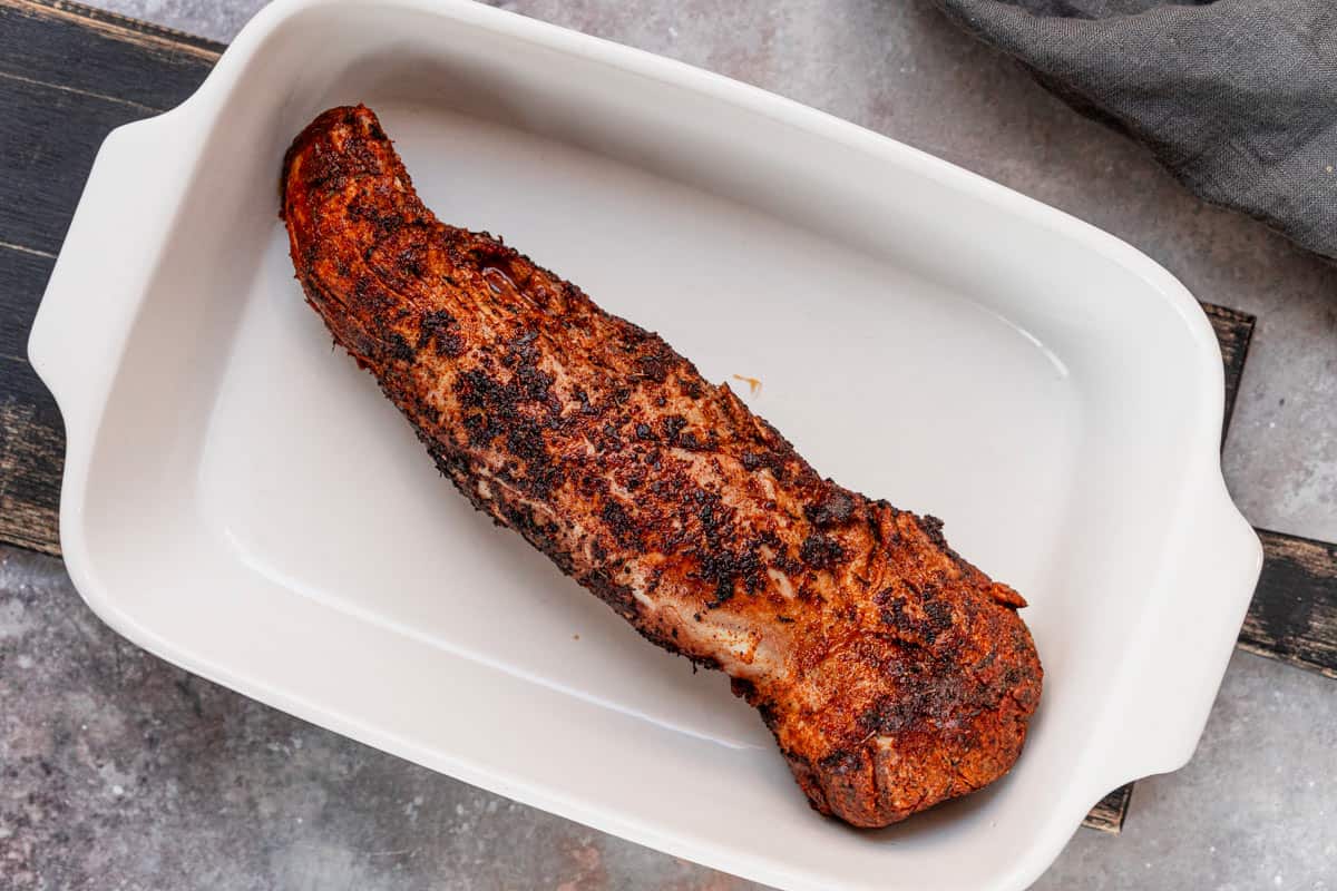 preparing pork tenderloin to bake in oven dish.