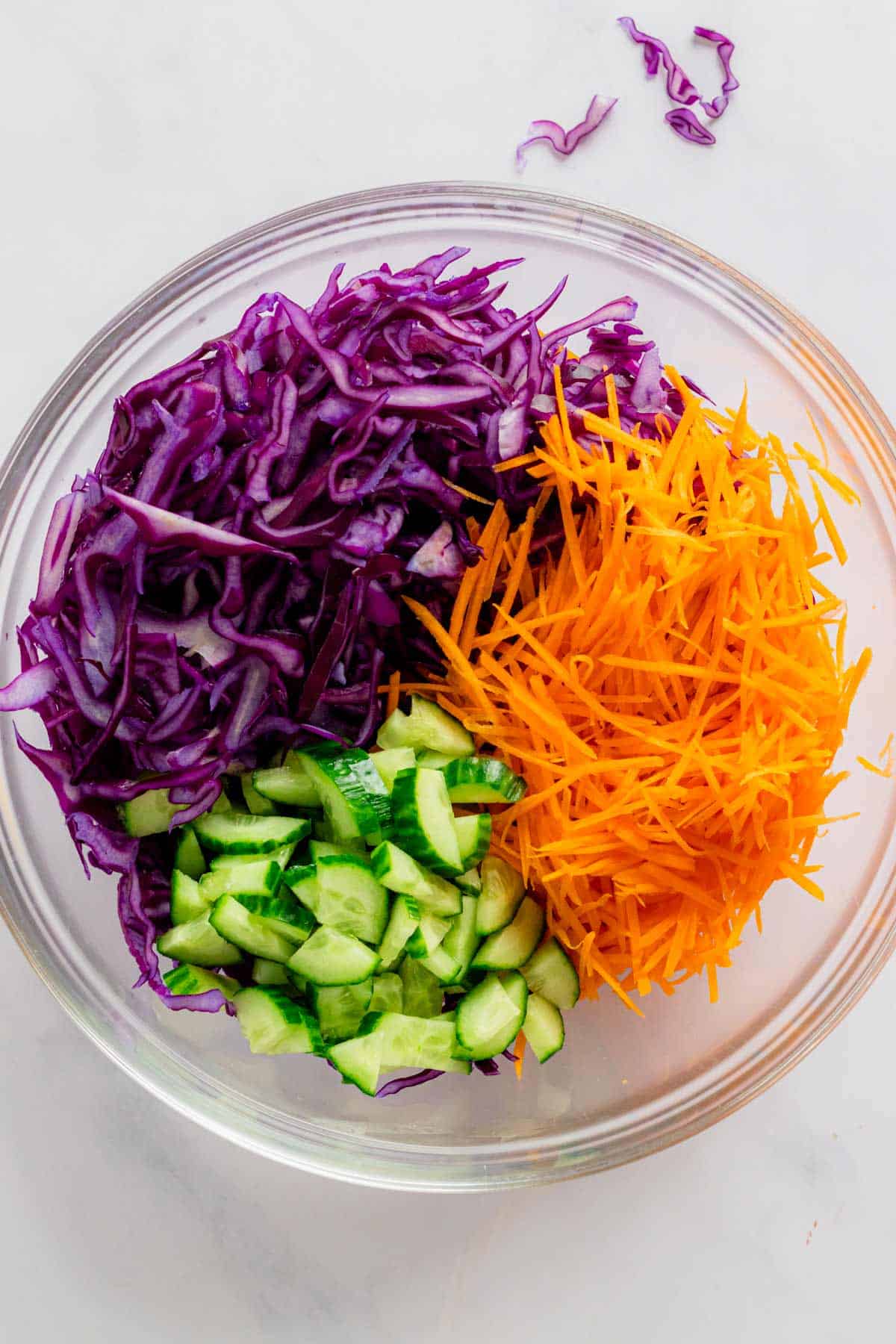 shredded cabbage, carrots and cucumbers in a bowl.