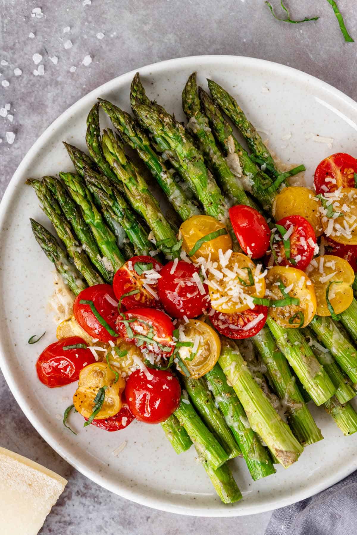 flat lay shot of plated final roasted asparagus with tomatoes, parmesan and basil leaves