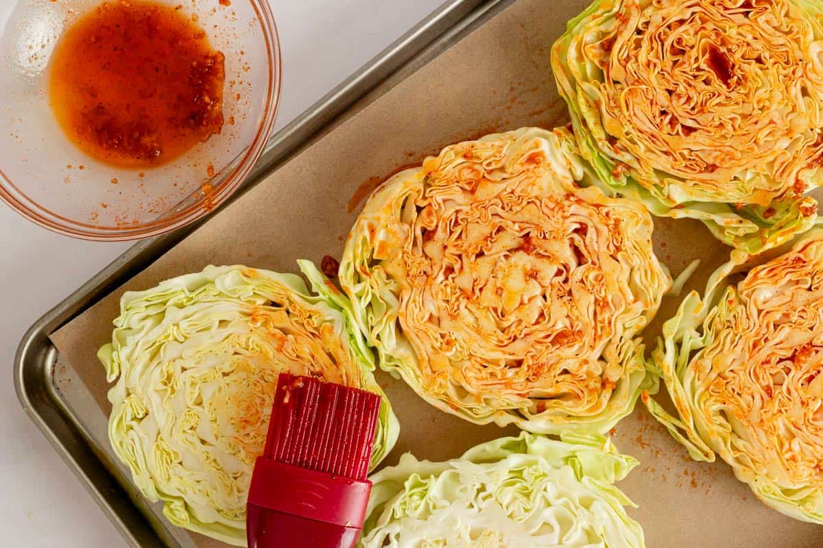 brushing the raw cabbage steaks with paprika seasoning