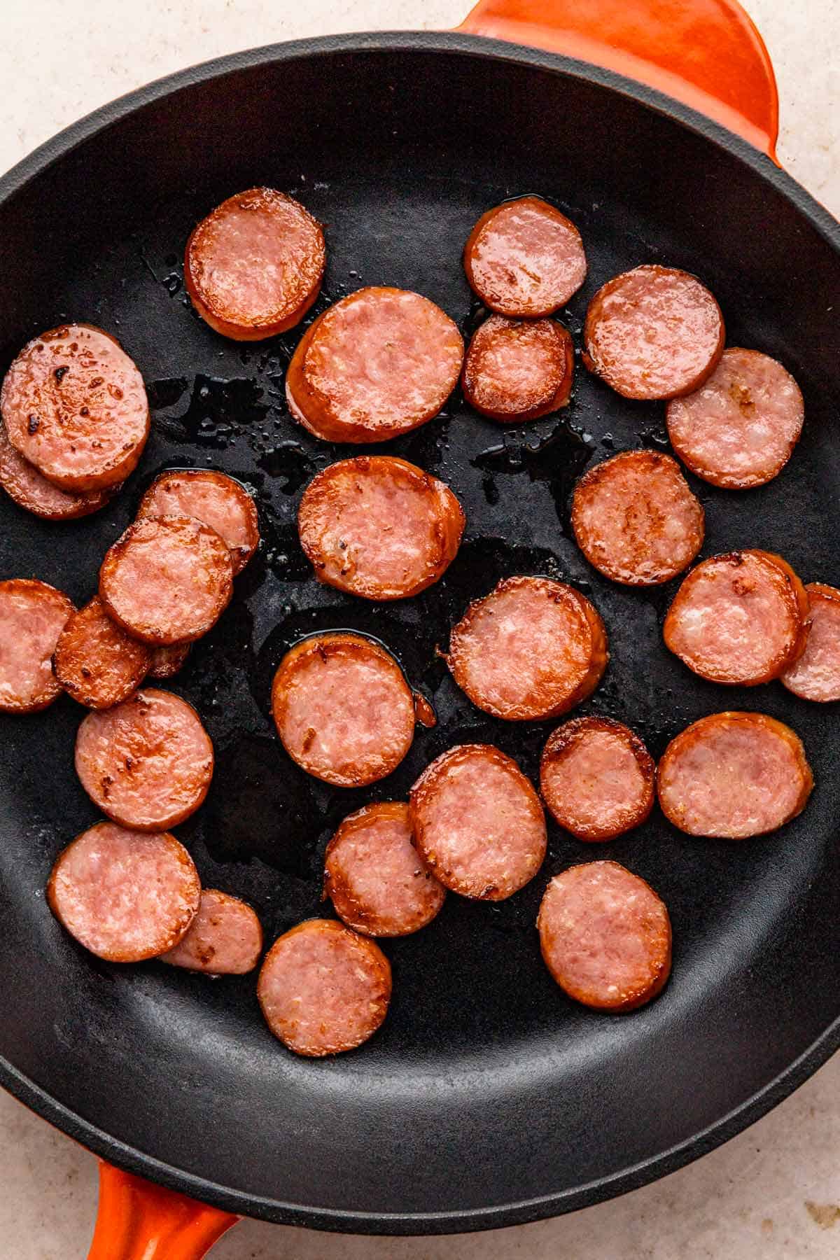 cooking kielbasa slices in skillet.