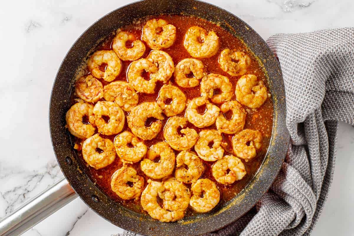 shrimp cooking in fajita seasoning in a skillet