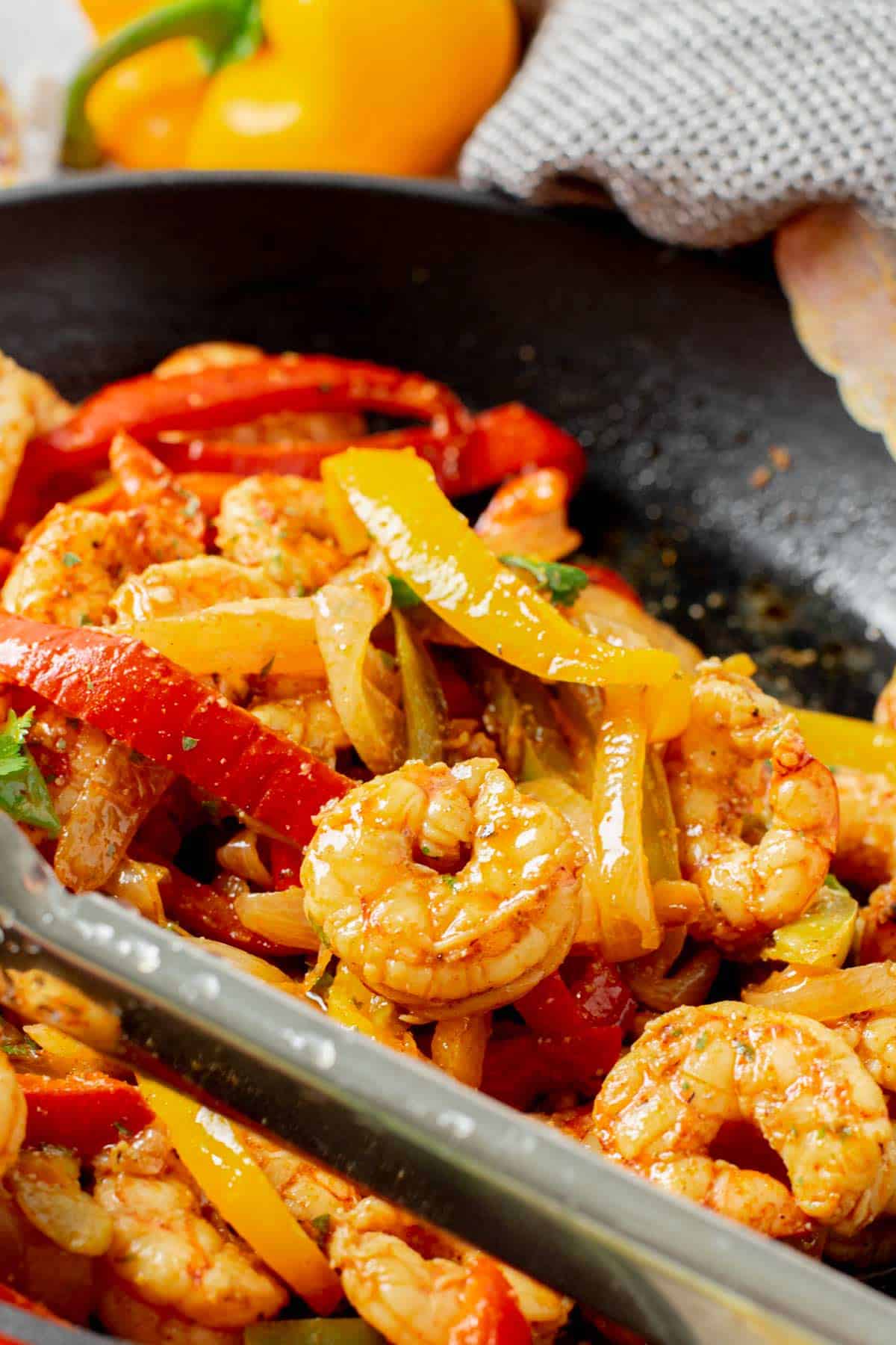 close up shot of taking a spoonful of shrimp fajita froma skillet